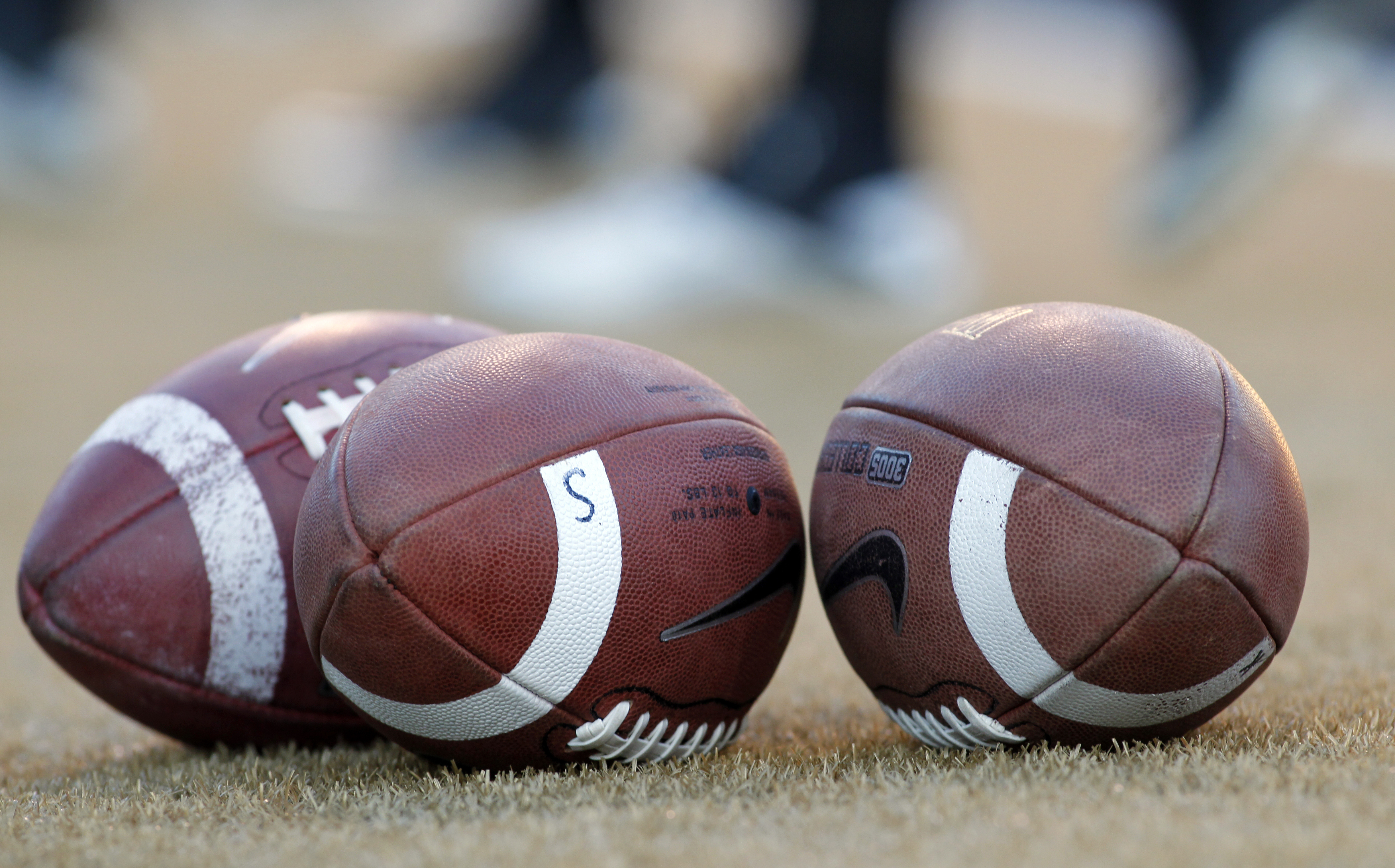 FILE - Footballs stand ready before the Virginia Tech at Wake Forest NCAA college football game in Winston-Salem, N.C., Saturday Oct. 15, 2011. A settlement being discussed in an antitrust lawsuit against the NCAA and major college conferences could cost billions and pave the way for a new compensation model for college athletes. 