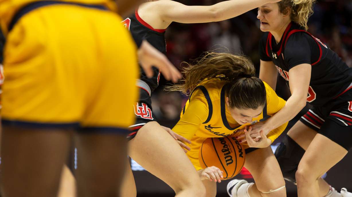 California guard Kemery Martín (15) is defended by Utah forward Reese Ross (20), left, and guard Matyson Wilke (23), right, at University of Utah’s Huntsman Center in Salt Lake City on Jan. 14, 2024. Utah won 93-56.