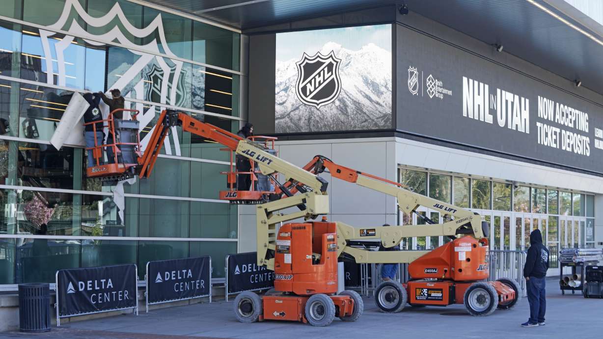 FILE - Workers put up signs celebrating the awarding of a new NHL team to Utah at the Delta Center Thursday, April 18, 2024, in Salt Lake City. It may look like an NHL team has just fallen into Salt Lake City's lap. But local organizers say the Arizona Coyotes' relocation to Utah is the product of a yearslong effort to beckon professional hockey and other elite sports to the capital city.