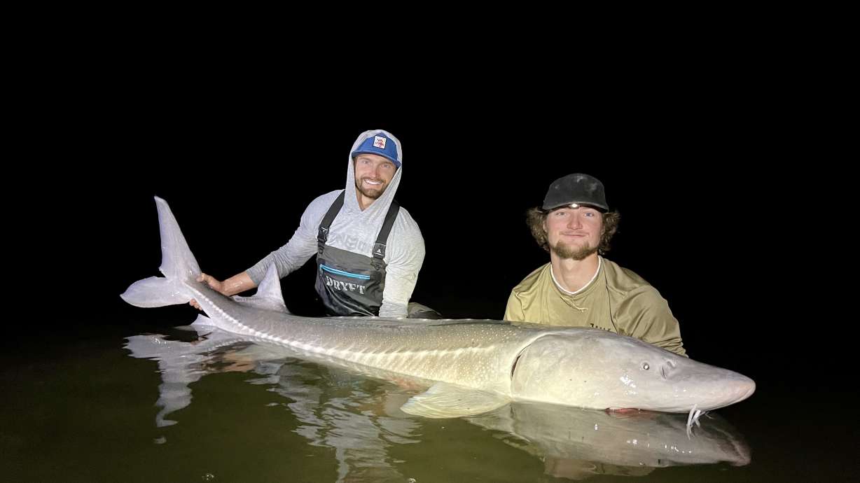 Zach Bush and Martin Chagnovich prepare to release a sturgeon they caught back into the Snake River.