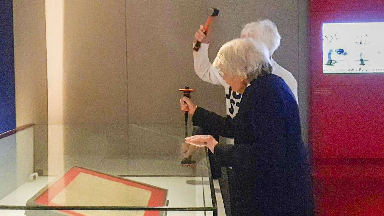 In this photo provided by Just Stop Oil on Friday, two activists target the protective enclosure around the historic Magna Carta document with a hammer at the British Library in London.