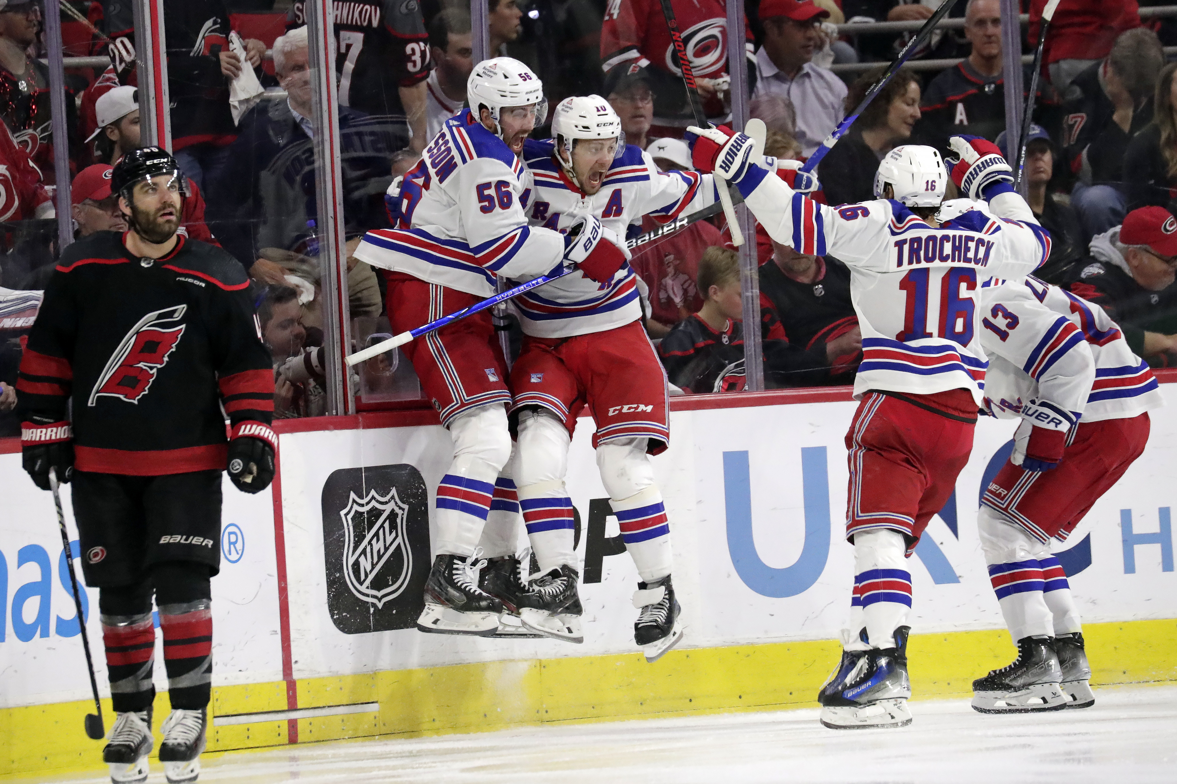 New York Rangers defenseman Erik Gustafsson (56), left wing Artemi Panarin, center Vincent Trocheck (16) and left wing Alexis Lafrenière (13) celebrate after scoring the winning goal in the overtime period in Game 3 of an NHL hockey Stanley Cup second-round playoff series Thursday, May 9, 2024, in Raleigh, N.C. Carolina Hurricanes left wing Jordan Martinook skates away at left.