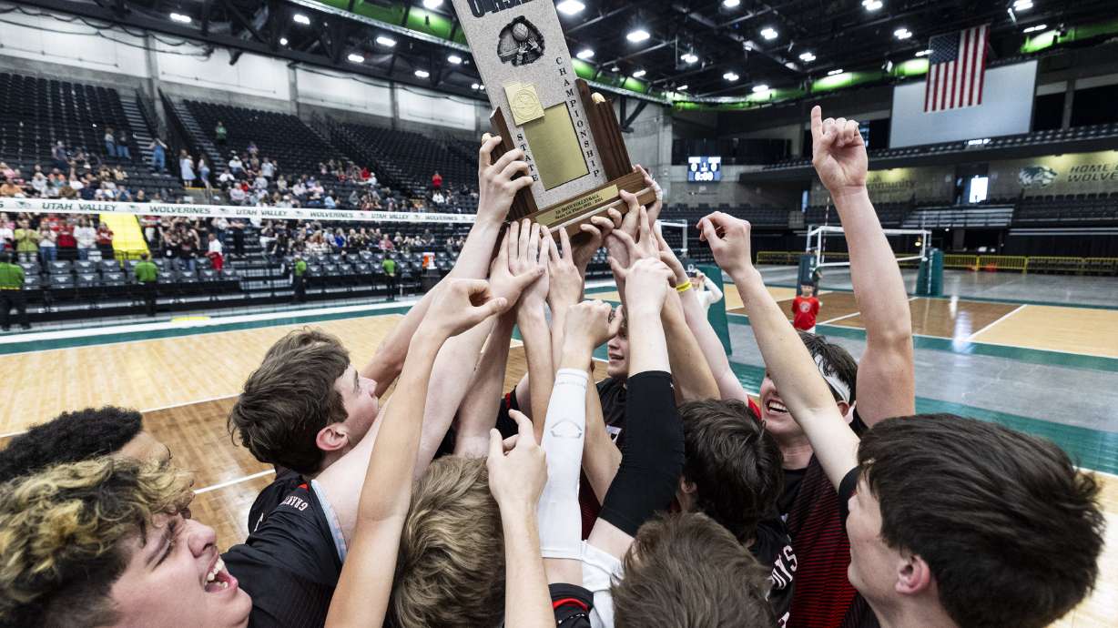 Grantsville players surround the championship trophy after defeating North Sanpete in the 3A boys volleyball state championship held at the UCCU Center in Orem on Saturday, May 11, 2024.