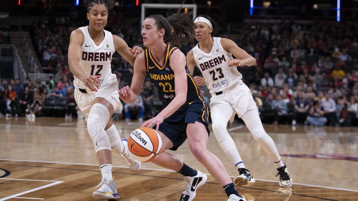 Indiana Fever's Caitlin Clark (22) goes to the basket against Atlanta Dream's Nia Coffey (12) and Aerial Powers (23) during the second half of a WNBA preseason basketball game Thursday, May 9, 2024, in Indianapolis.