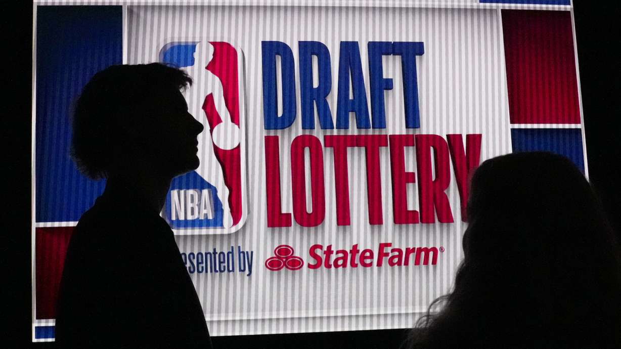 NBA basketball draft prospect Johnny Furphy, left, looks at the draft lottery order in front of a draft lottery sign before the draft lottery in Chicago, Sunday, May 12, 2024.