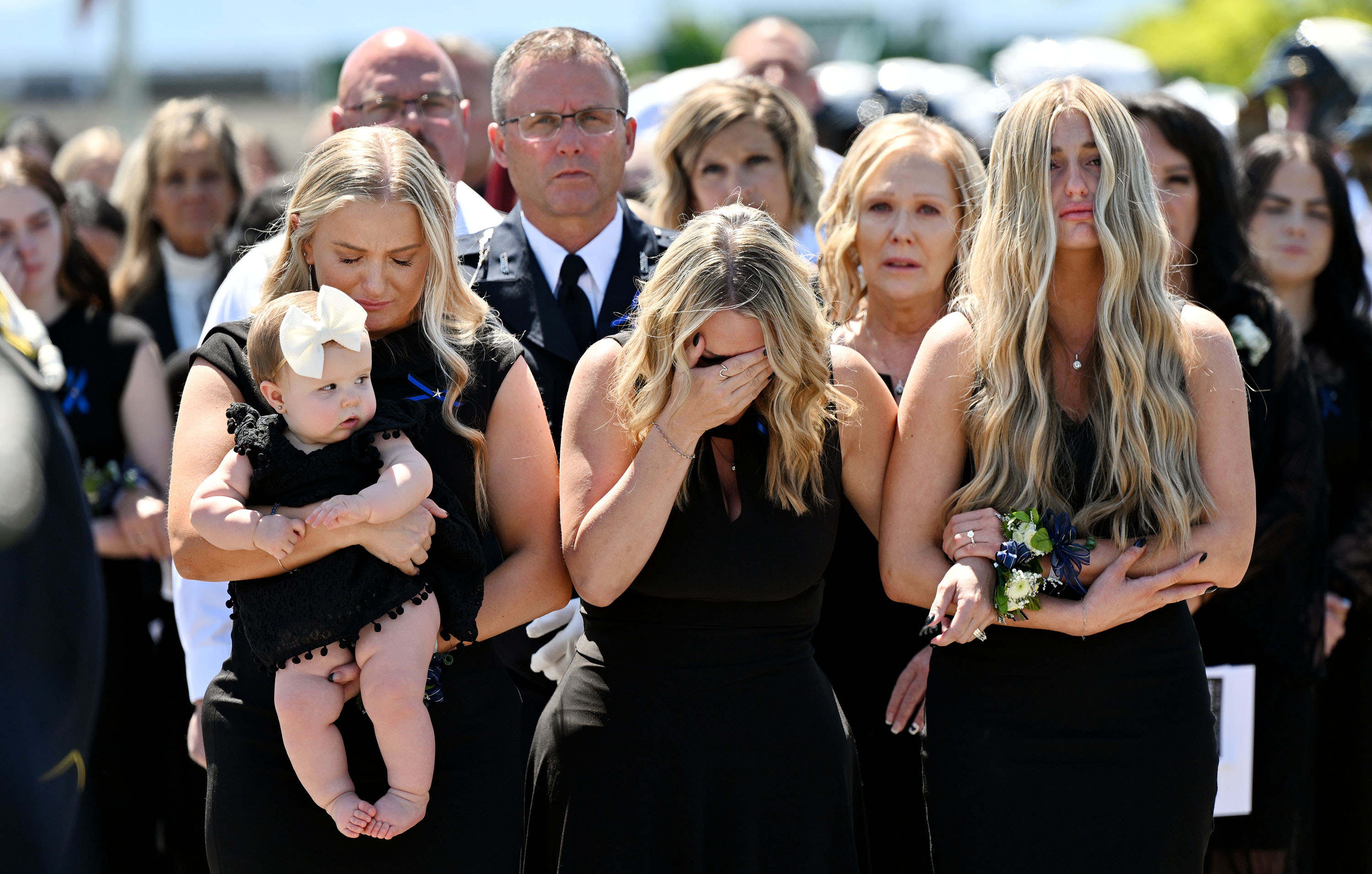 Kinda Hooser walks with her daughter Shayle Terry, holding granddaughter Paxton, and daughter Courtney Hooser as they follow the casket of Santaquin Police Sgt. Bill Hooser after funeral services in Orem Monday.