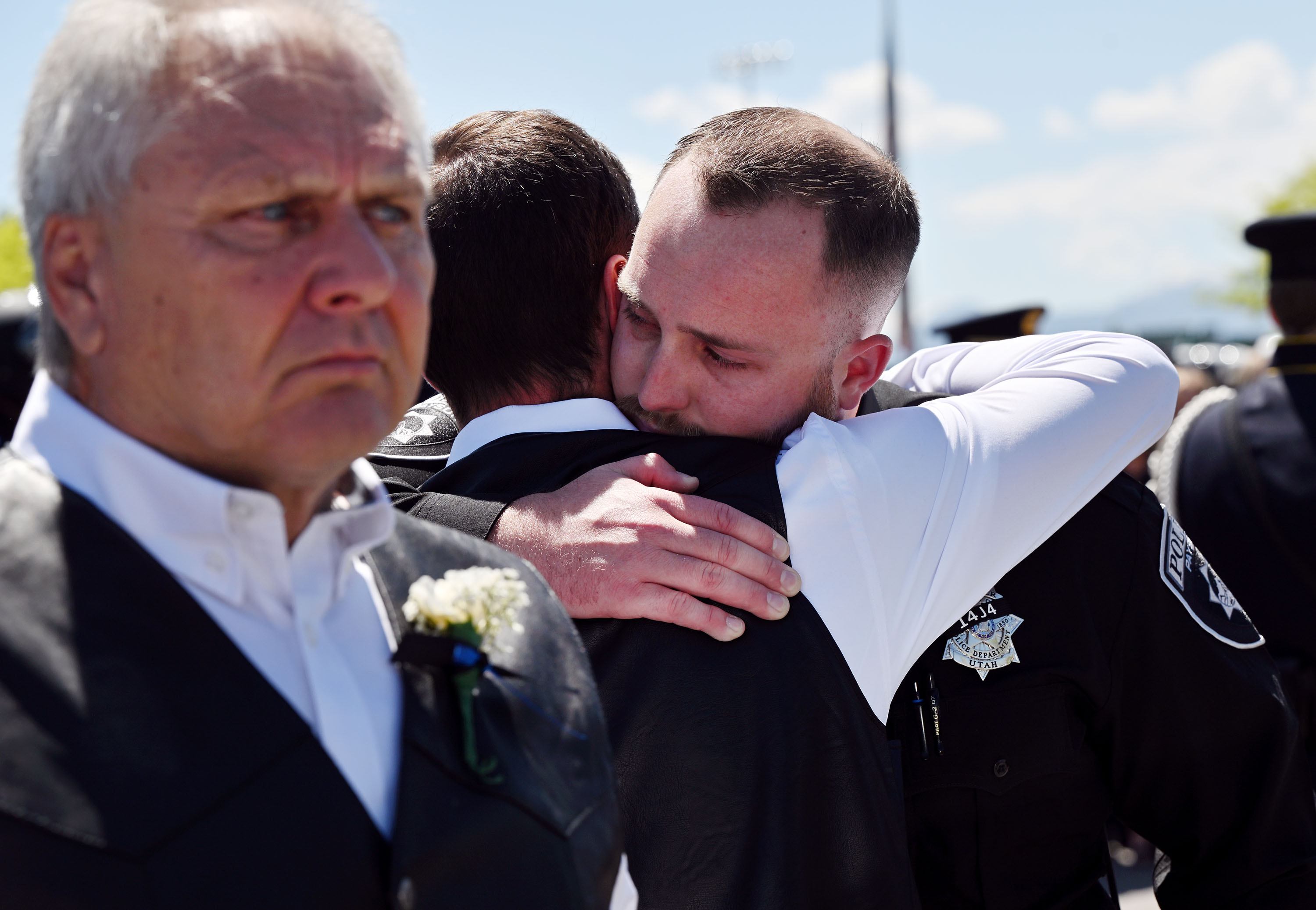 Family members and officers hug after funeral services for Santaquin Police Sgt. Bill Hooser at the UCCU Center at UVU in Orem on Monday.