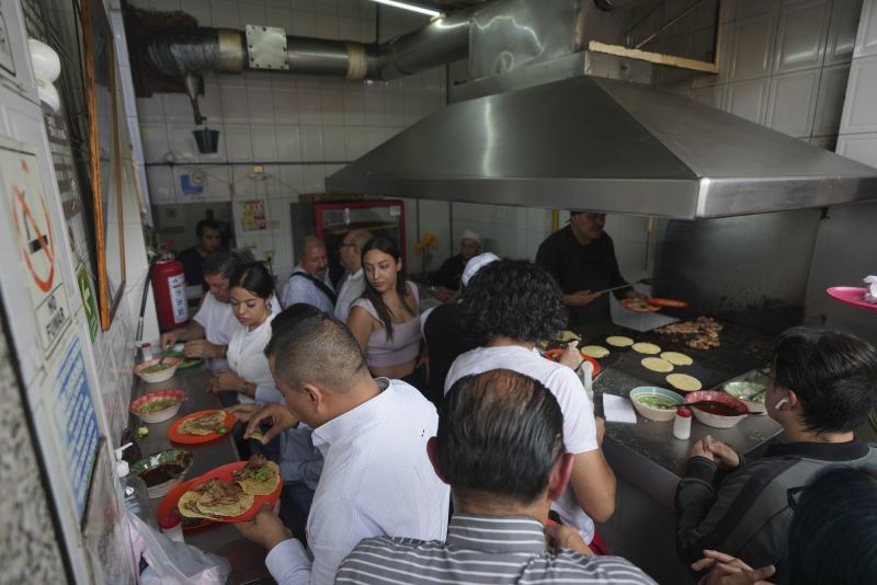 People are seen at Tacos El Califa de León taco stand, in Mexico City, Wednesday.