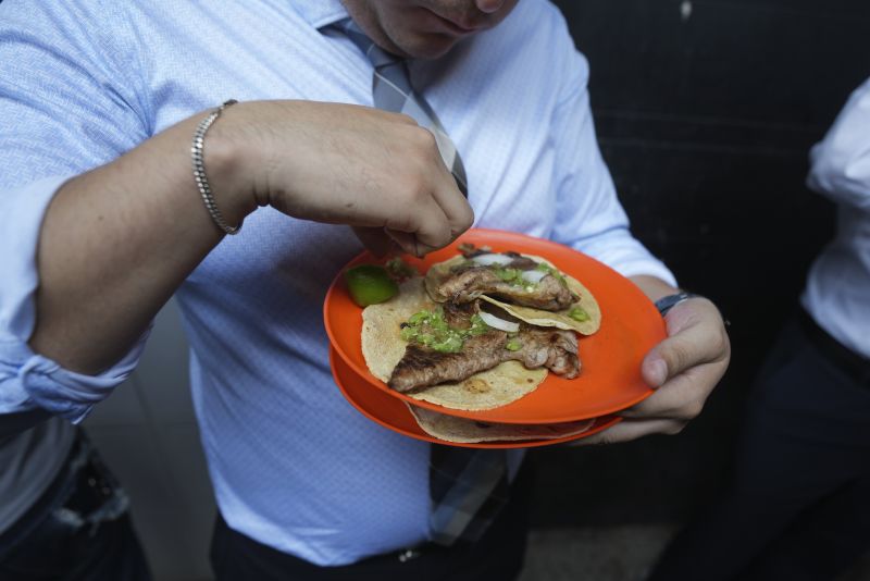 A customer finishes squeezing lime juice on his tacos at the Tacos El Califa de León stand, in Mexico City, Wednesday. Tacos El Califa de León is the first ever taco stand to receive a Michelin star from the French dining guide.