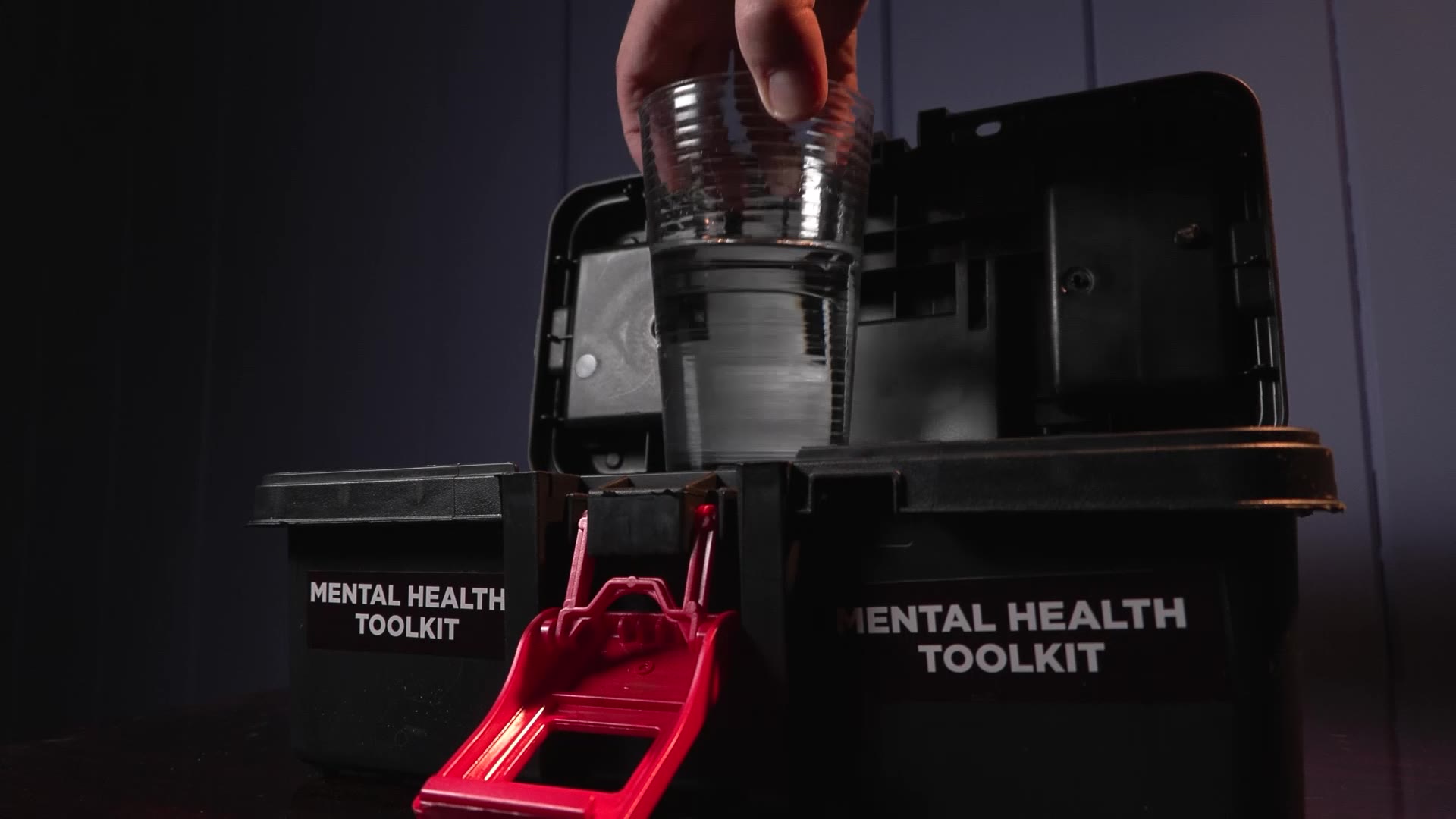 A glass of water being pulled out of a mental health kit as a reminder to keep hydrated.