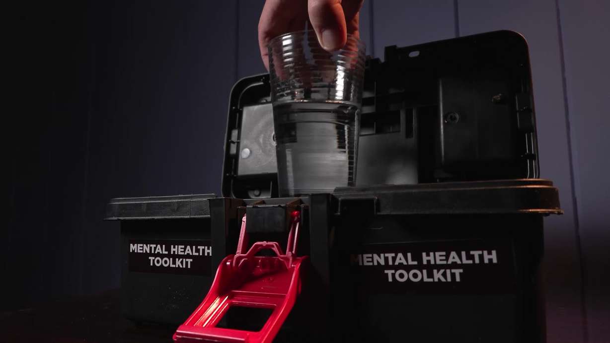 A glass of water being pulled out of a mental health kit as a reminder to keep hydrated.