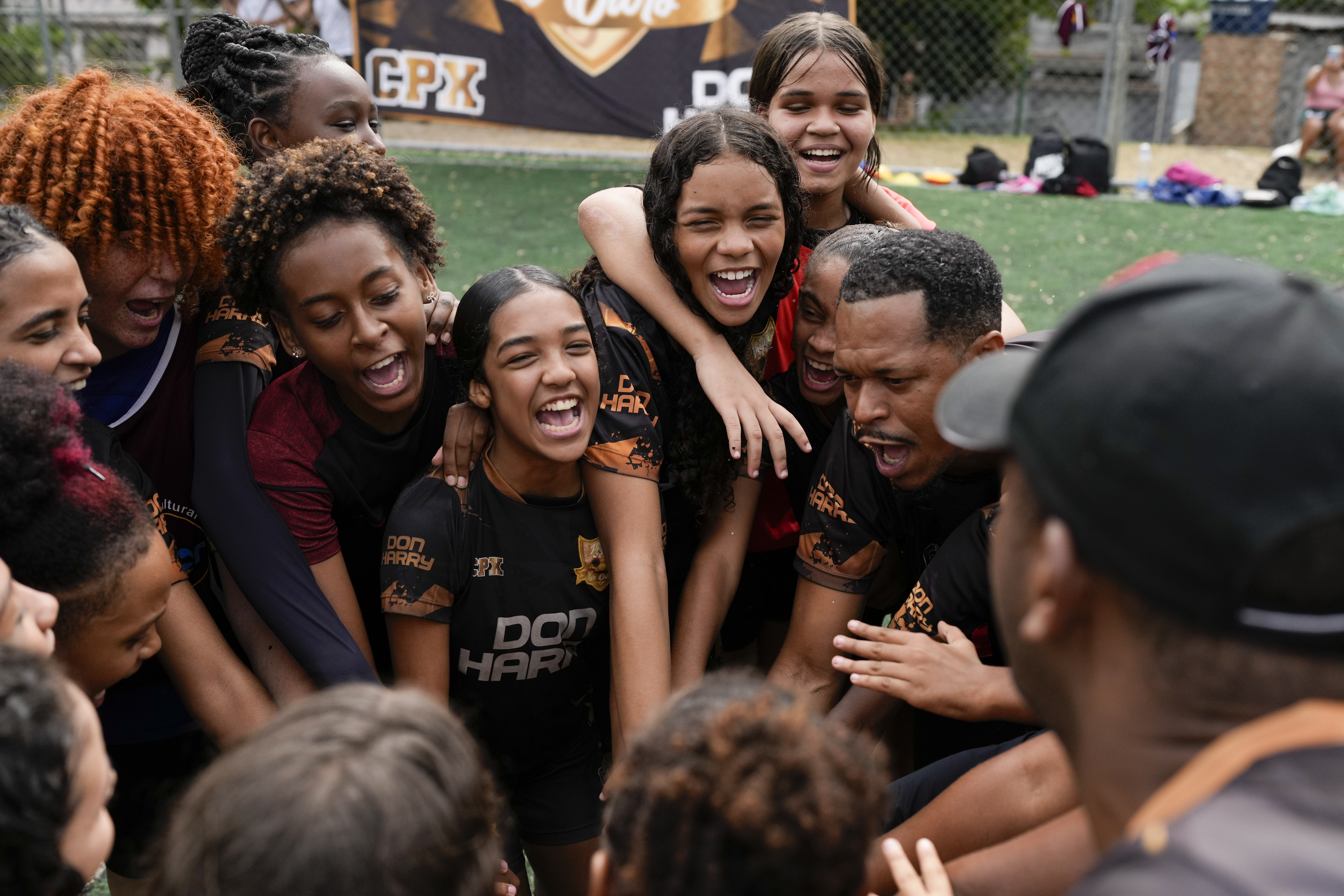 Young women and their coach Dioguinho bring it in for a team huddle at the start of a soccer training session run by the Bola de Ouro social program, at the Complexo da Alemao favela in Rio de Janeiro, Brazil, May 16, 2024. Young women are participating in soccer programs led by community trainers, where they receive both sports and personal development training. 