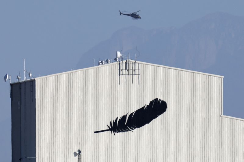 A helicopter flies over a building featuring Blue Origin's logo near Van Horn, Texas, Oct. 13, 2021.