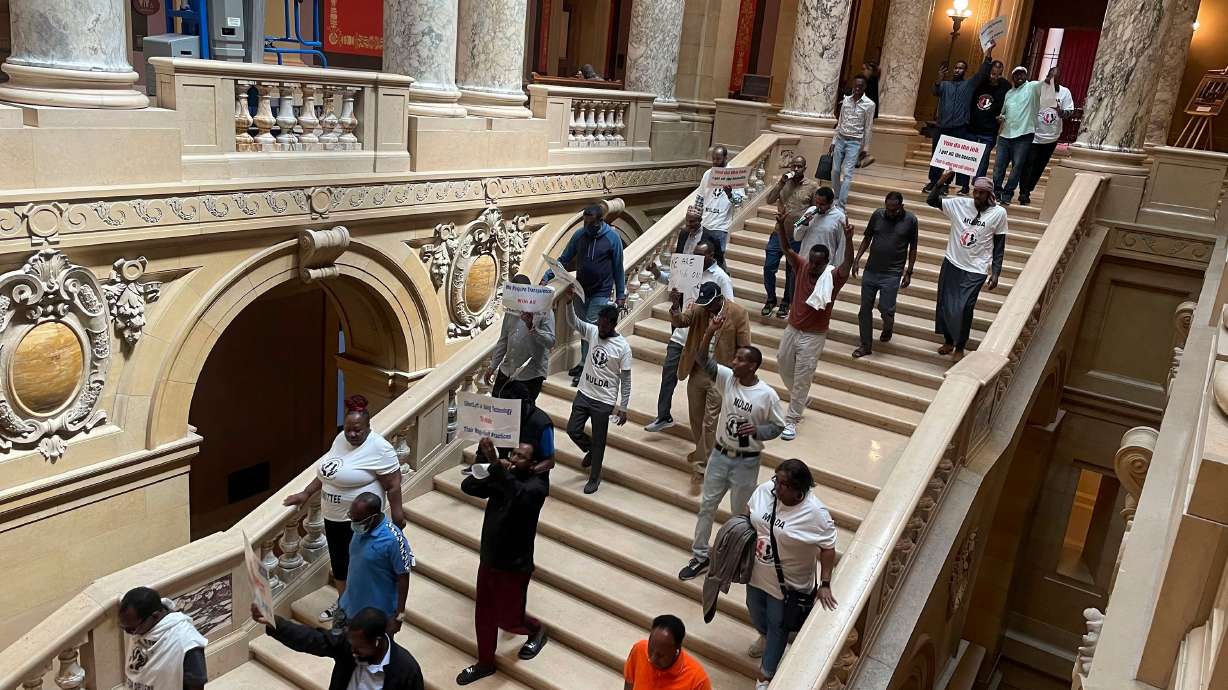 Protesters descend a staircase in the Minnesota State Capitol building in St. Paul, holding signs and pushing for a law which would require ride-hailing companies – including Uber and Lyft – to increase pay for drivers in the state.