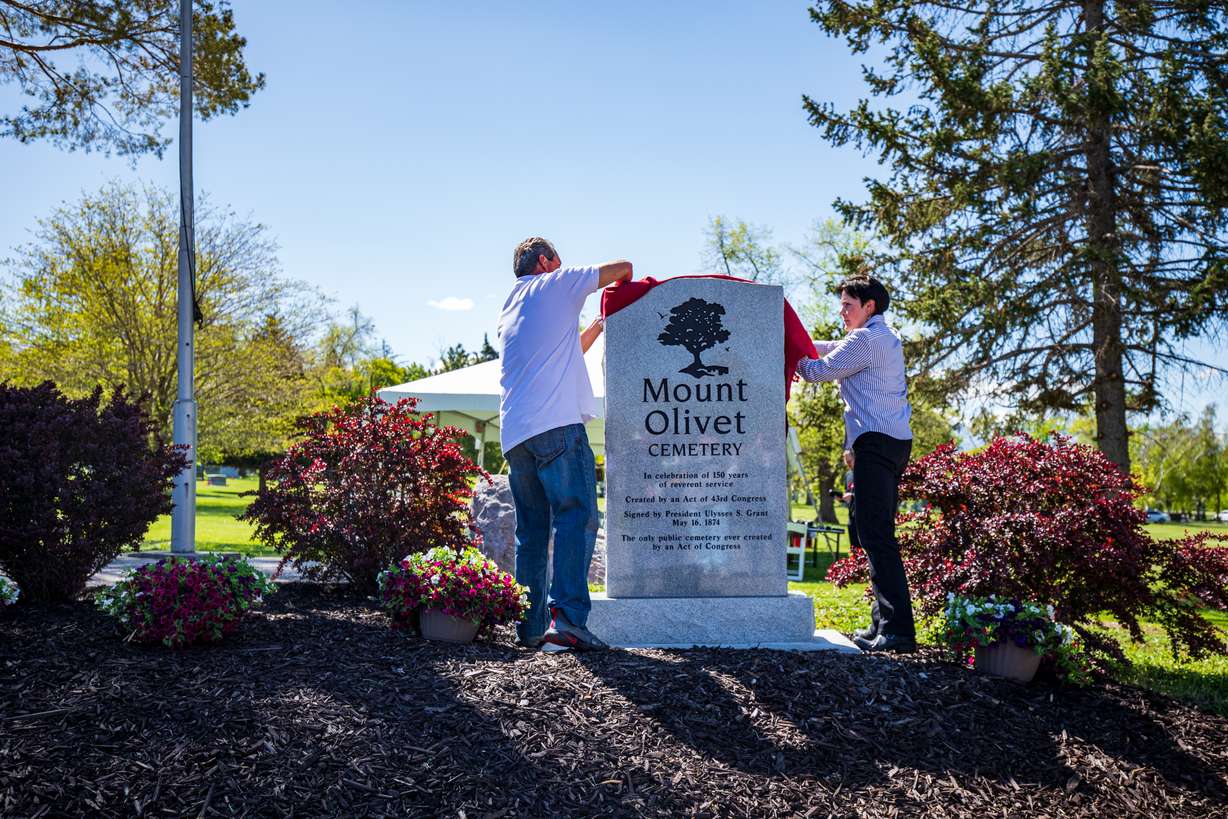 Mount Olivet Cemetery sexton Danny Valdez and his wife, Pamela, unveil a monument commemorating the cemetery's 150th anniversary during a dedication ceremony on May 11.