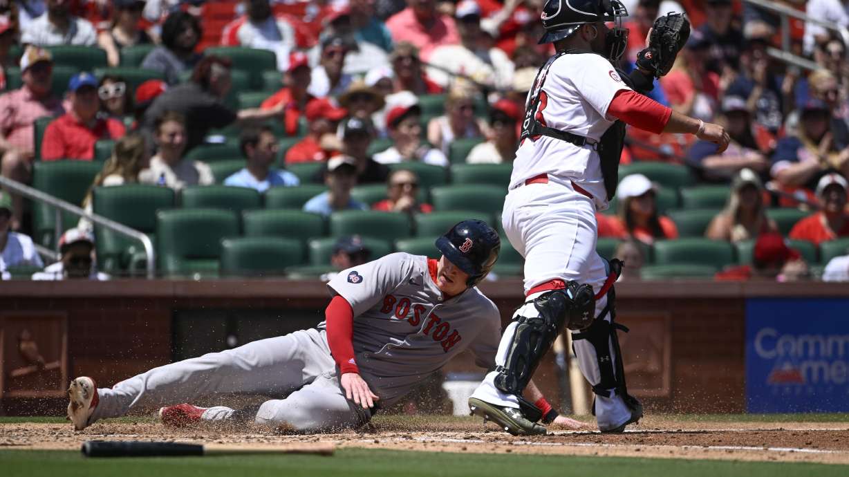 Boston Red Sox's Garrett Cooper, left, slides safely into home plate for a run ahead of the tag by St. Louis Cardinals catcher Pedro Pages, right, in the fourth inning of a baseball game Sunday, May 19, 2024, in St. Louis.