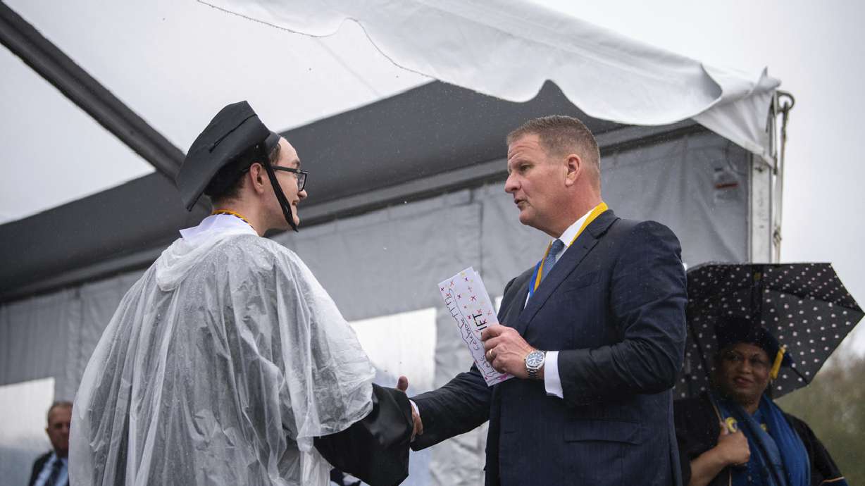 Billionaire Robert Hale, right, with a graduate student onstage at the graduation ceremony, May 16, in Dartmouth, Mass. Hale gifted graduates each with $1,000.