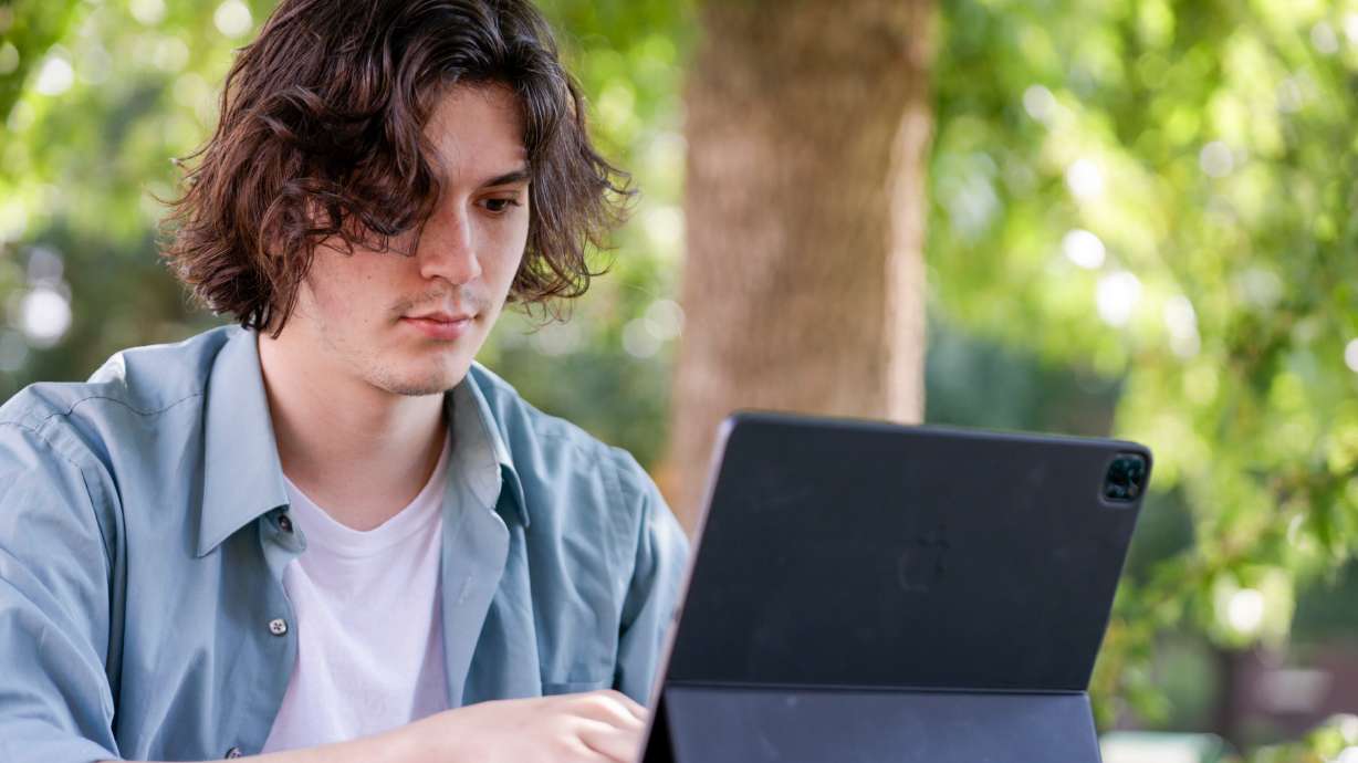 Jason Flechsing, a senior at Boise State University, does class work in Boise on Sept. 22, 2022. Sen. Mitt Romney is urging President Joe Biden to halt the latest plan for student debt relief.