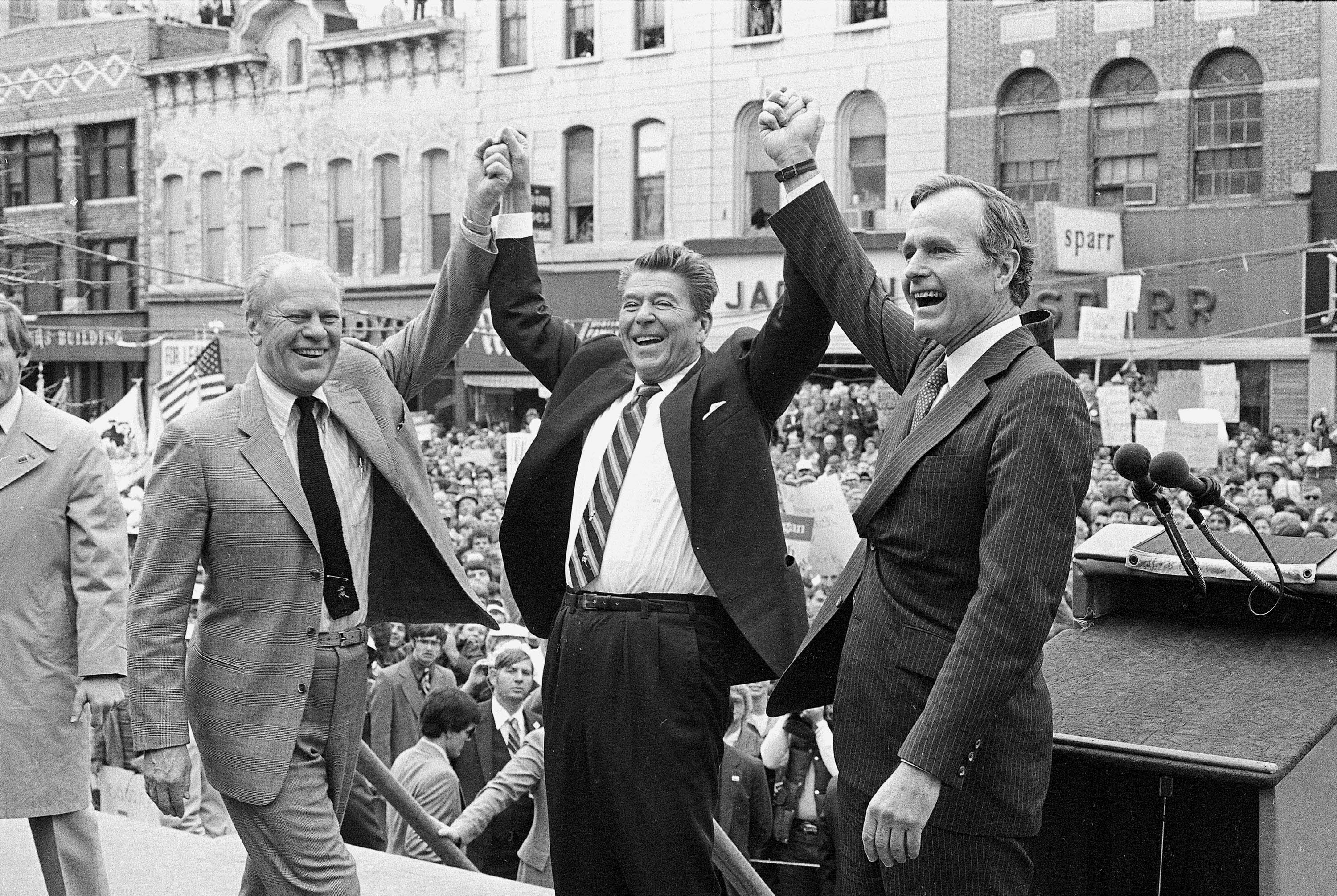 Former President Gerald R. Ford, left, lends his support to fellow Republican and then-presidential candidate Ronald Reagan and running mate George Bush, seen here on the final day of campaigning in Peoria, Ill., Nov. 3, 1980.