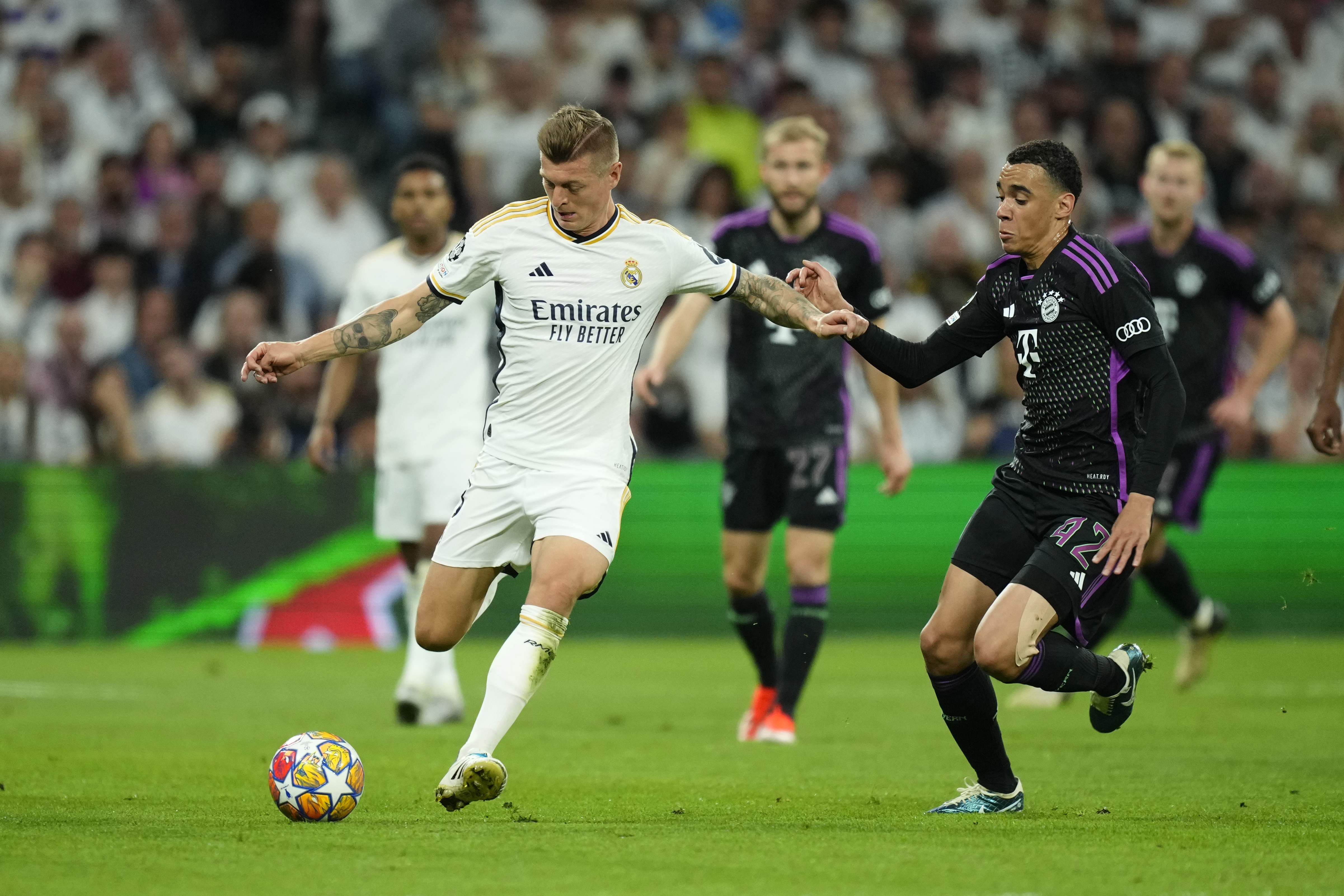 Real Madrid's Toni Kroos, left, challenges for the ball with Bayern's Jamal Musiala during the Champions League semifinal second leg soccer match between Real Madrid and Bayern Munich at the Santiago Bernabeu stadium in Madrid, Spain, Wednesday, May 8, 2024. 