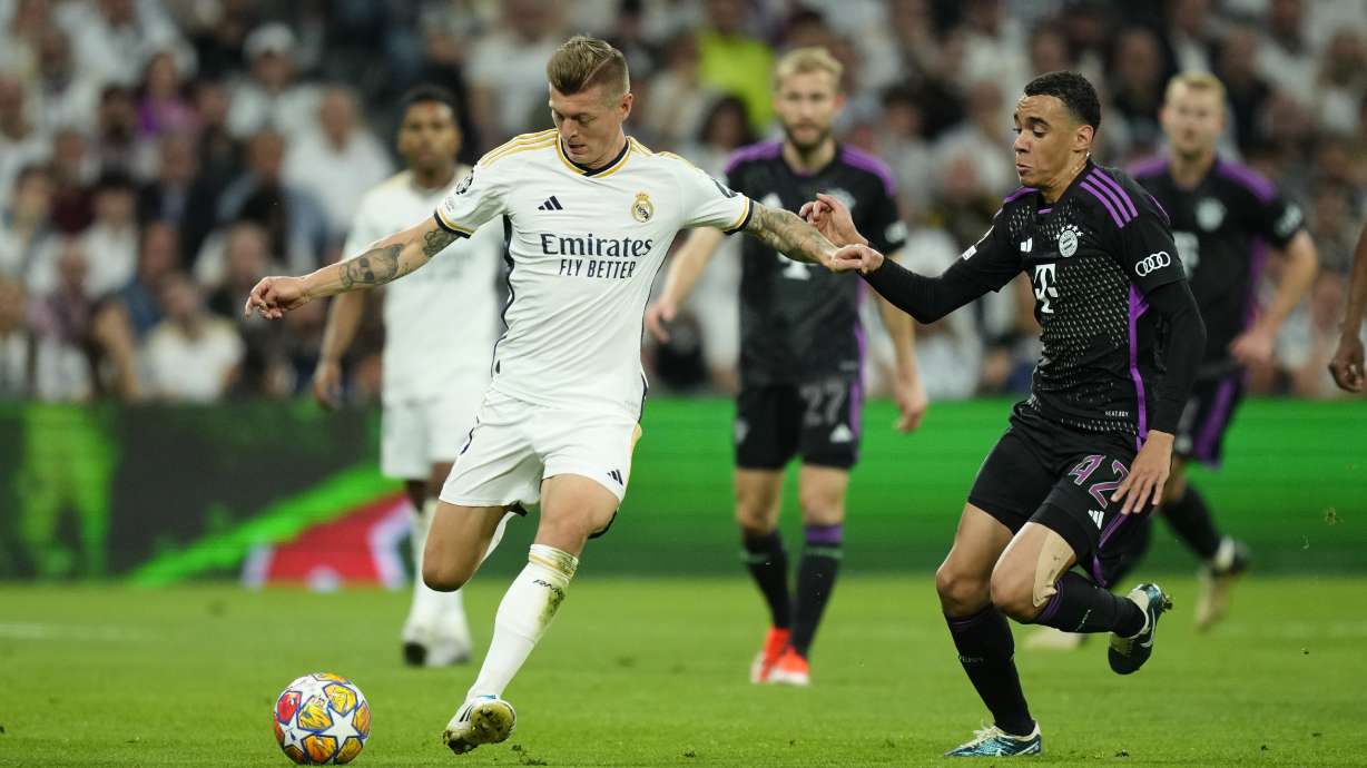 Real Madrid's Toni Kroos, left, challenges for the ball with Bayern's Jamal Musiala during the Champions League semifinal second leg soccer match between Real Madrid and Bayern Munich at the Santiago Bernabeu stadium in Madrid, Spain, Wednesday, May 8, 2024.