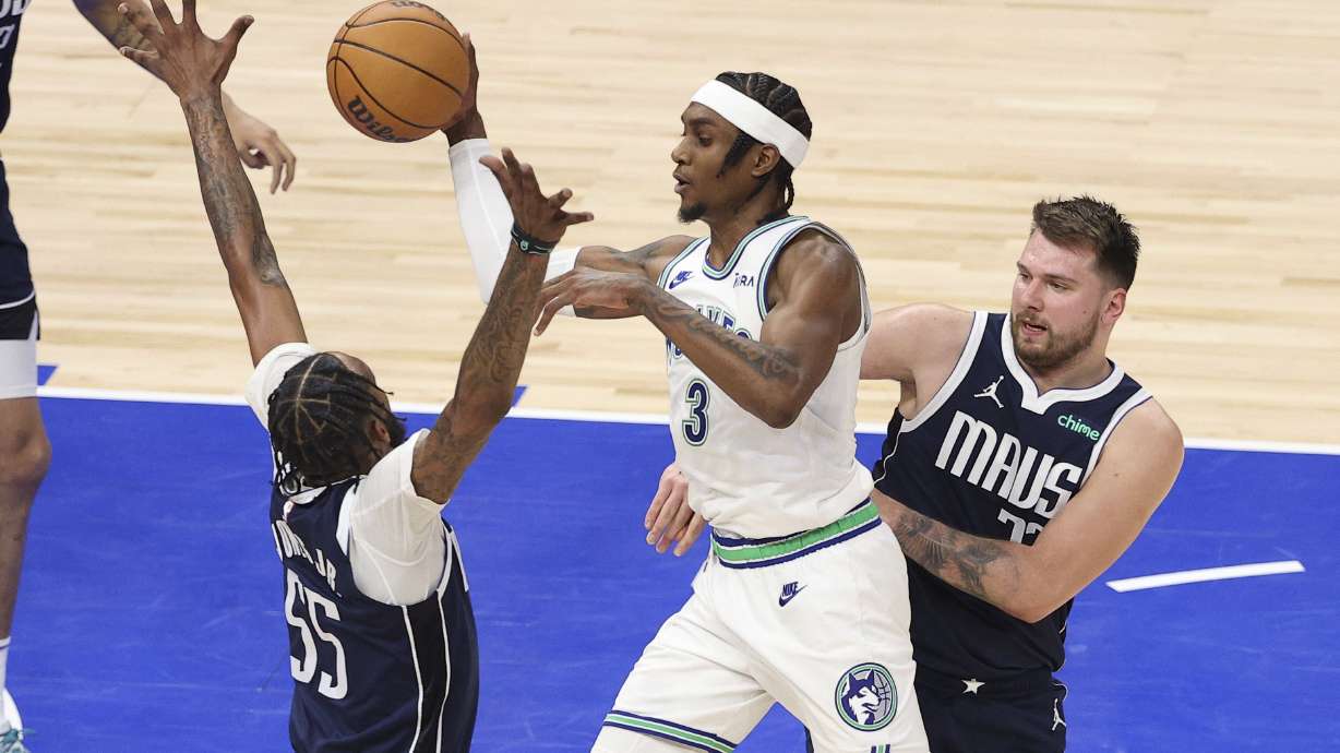 Minnesota Timberwolves forward Jaden McDaniels (3) drives between Dallas Mavericks forward Derrick Jones Jr. (55) and guard Luka Doncic, right, during Game 1 of the NBA basketball Western Conference finals, Wednesday, May 22, 2024, in Minneapolis.