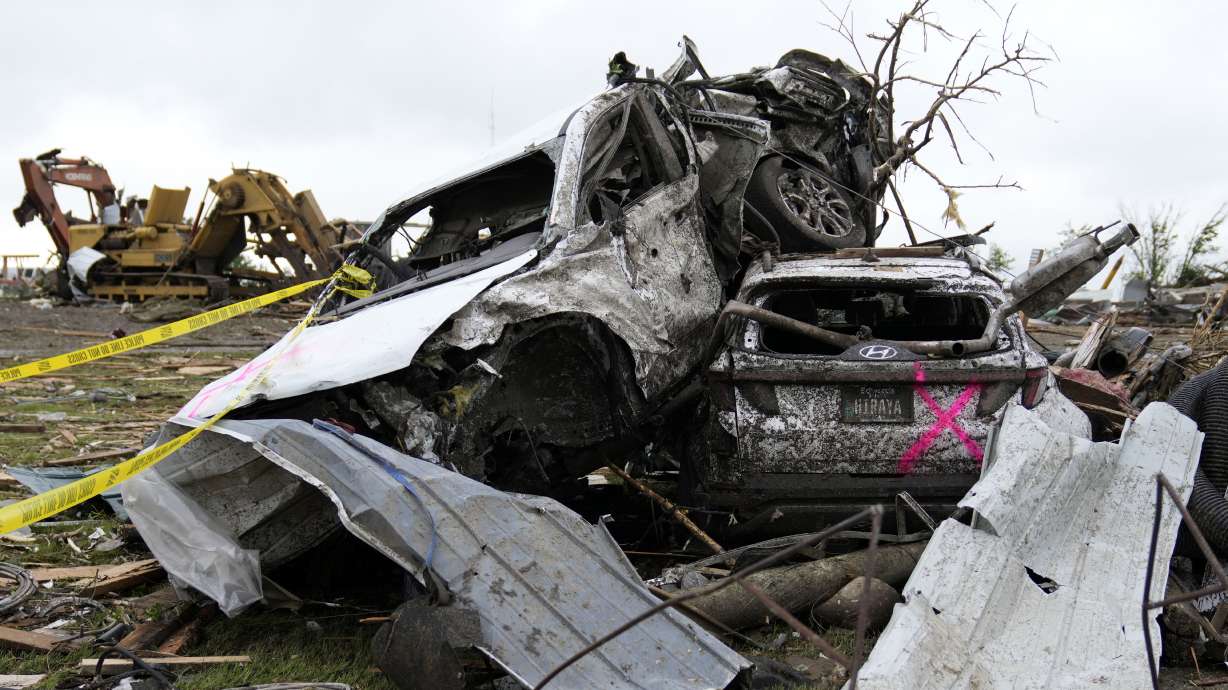 Damaged cars sit piled up next to a road after a tornado Tuesday, in Greenfield, Iowa. The tornado left four people dead and nearly three dozen injured, while a fifth person was killed elsewhere.