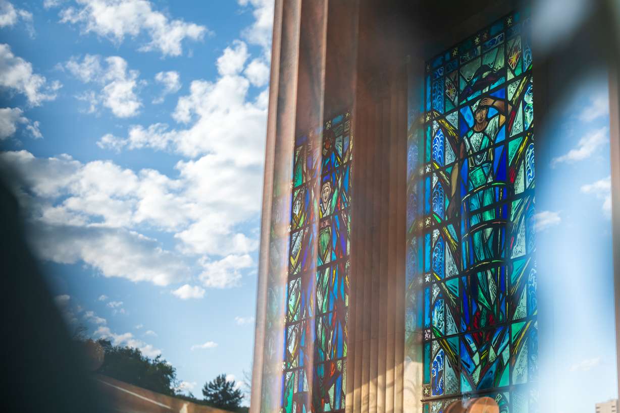 Stained glass windows representing different branches of the military inside the Memory Grove Meditation Chapel are seen from the outside while the sky and parts of the building are also reflected. The chapel was dedicated in 1948 for World War II soldiers who were listed missing in action at the time.