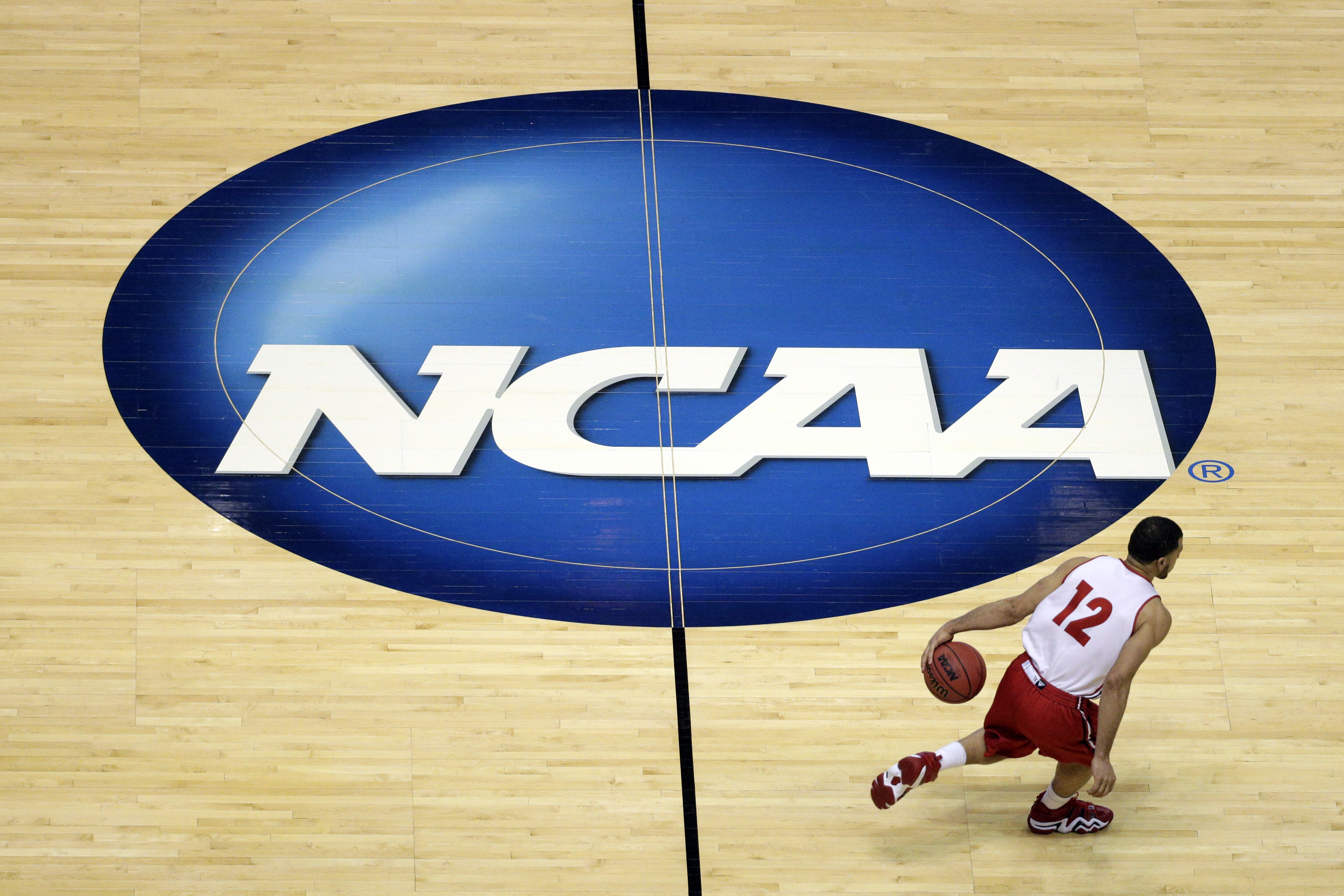 FILE - Wisconsin's Traevon Jackson dribbles past the NCAA logo during practice at the NCAA men's college basketball tournament March 26, 2014, in Anaheim, Calif. University presidents around the country are scheduled to meet this week in May 2024, to vote on whether to accept a proposed settlement of an antitrust lawsuit that would cost the NCAA nearly $3 billion in damages. 