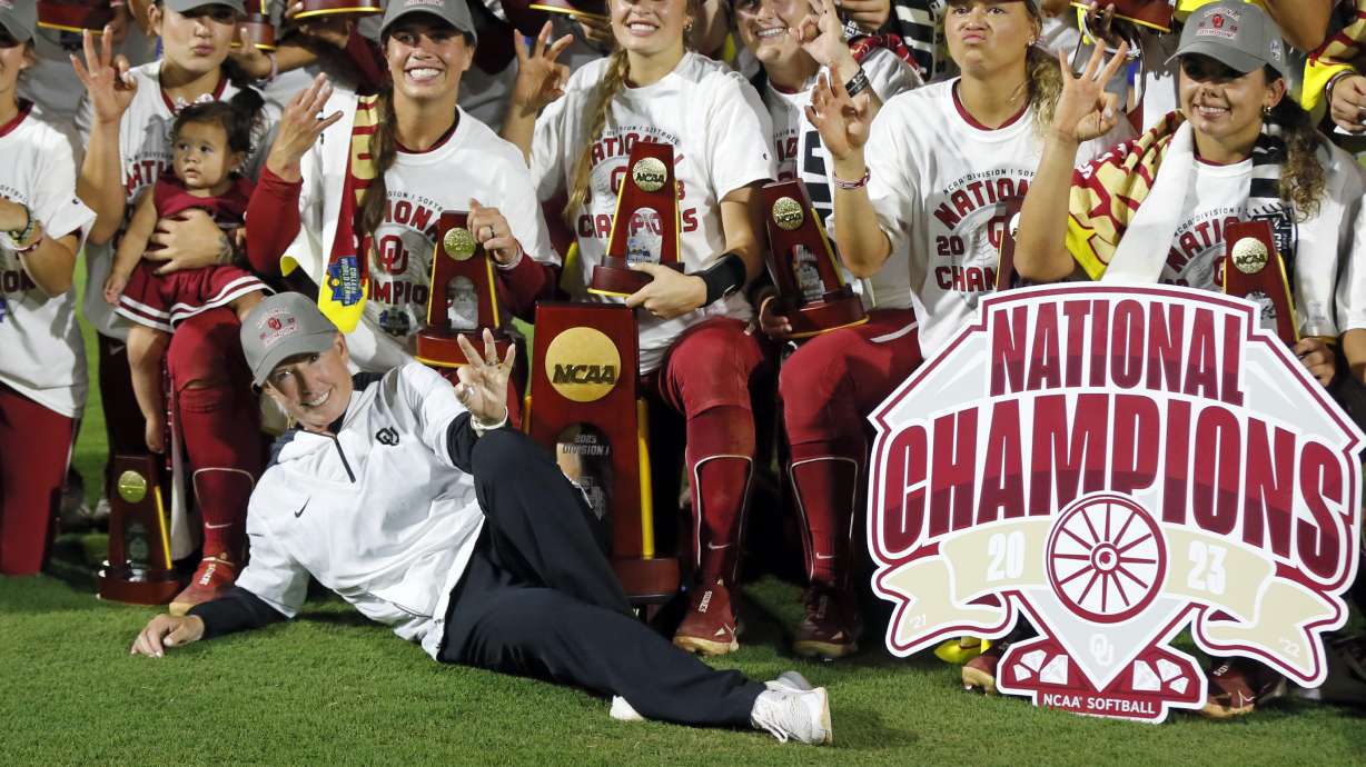FIKE - Oklahoma coach Patty Gasso, front left, and players pose for a photo while holding up three fingers after defeating Florida State in the NCAA Women's College World Series championship series Thursday, June 8, 2023, in Oklahoma City. Oklahoma begins its quest for an unprecedented fourth consecutive national softball title.