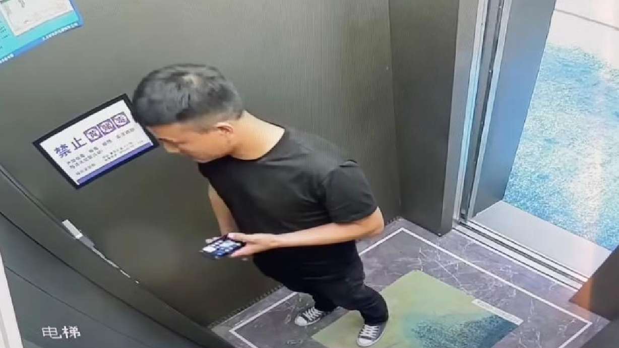 A man stands in an elevator seemingly completely unaware the door is open behind him.