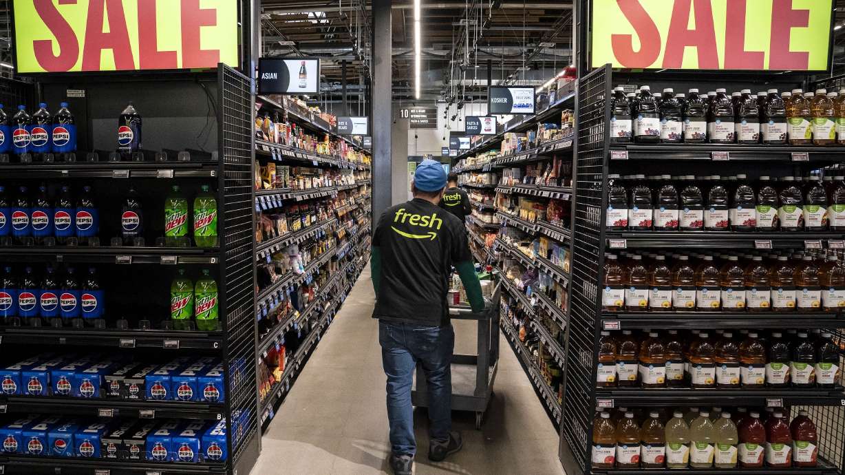 Workers stock shelves at an Amazon Fresh grocery store in Seattle on May 2. Amazon Fresh has joined the growing ranks of retailers that are cutting prices.