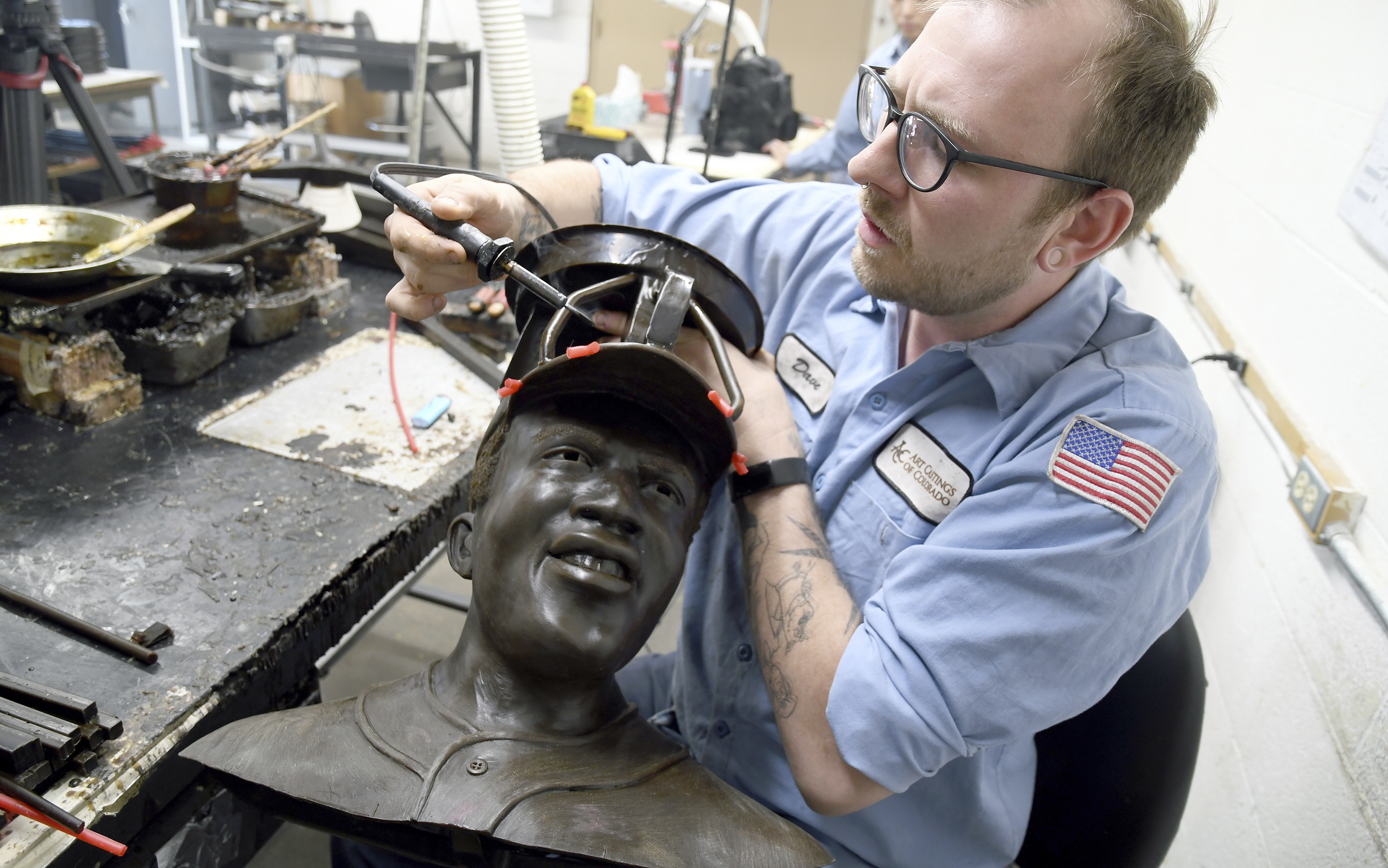David Hobbs, an employee at Art Castings of Colorado, touches up a wax mold of Jackie Robinson's head in Loveland, Colo. on Wednesday, May 8, 2024. The original statue was cut off at the ankles and stolen from a park in Wichita, Kansas in January. The Colorado foundry cast that sculpture in 2019 and, luckily, still had the original plaster and rubber molds. 