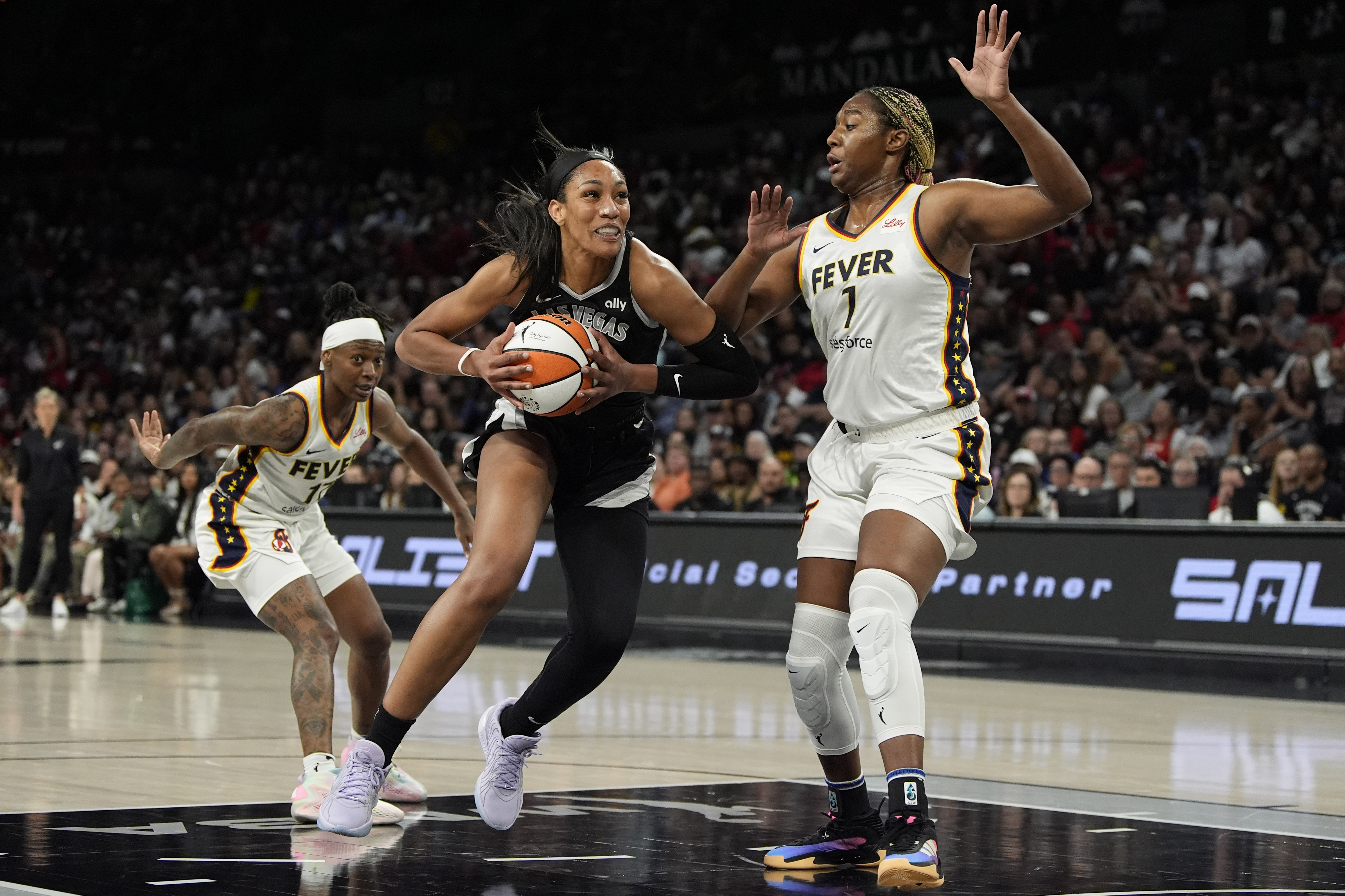 Las Vegas Aces center A'ja Wilson (22) drives against Indiana Fever forward NaLyssa Smith (1) during the first half of a WNBA basketball game Saturday, May 25, 2024, in Las Vegas. 