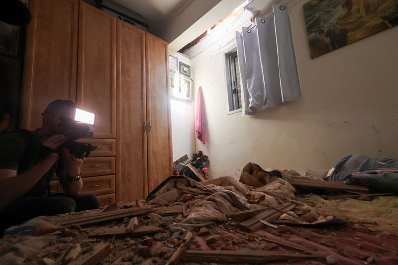 A media person works in a room that was damaged after rockets were fired from the Gaza Strip towards Israel, amid the ongoing conflict in Gaza between Israel and Palestinian Islamist group Hamas, in Herzliya, Israel, on Sunday.