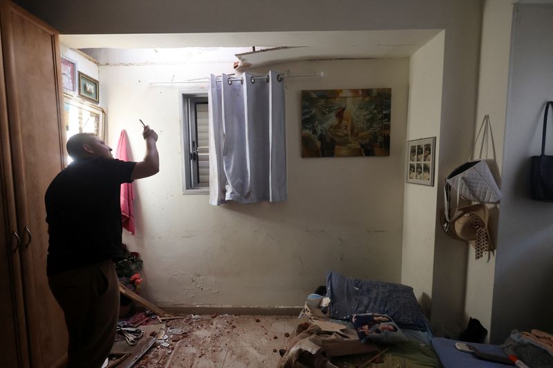 A person uses his phone to take pictures of the damage to a house after rockets were fired from the Gaza Strip towards Israel, amid the ongoing conflict in Gaza between Israel and Palestinian Islamist group Hamas, in Herzliya, Israel, on Sunday.