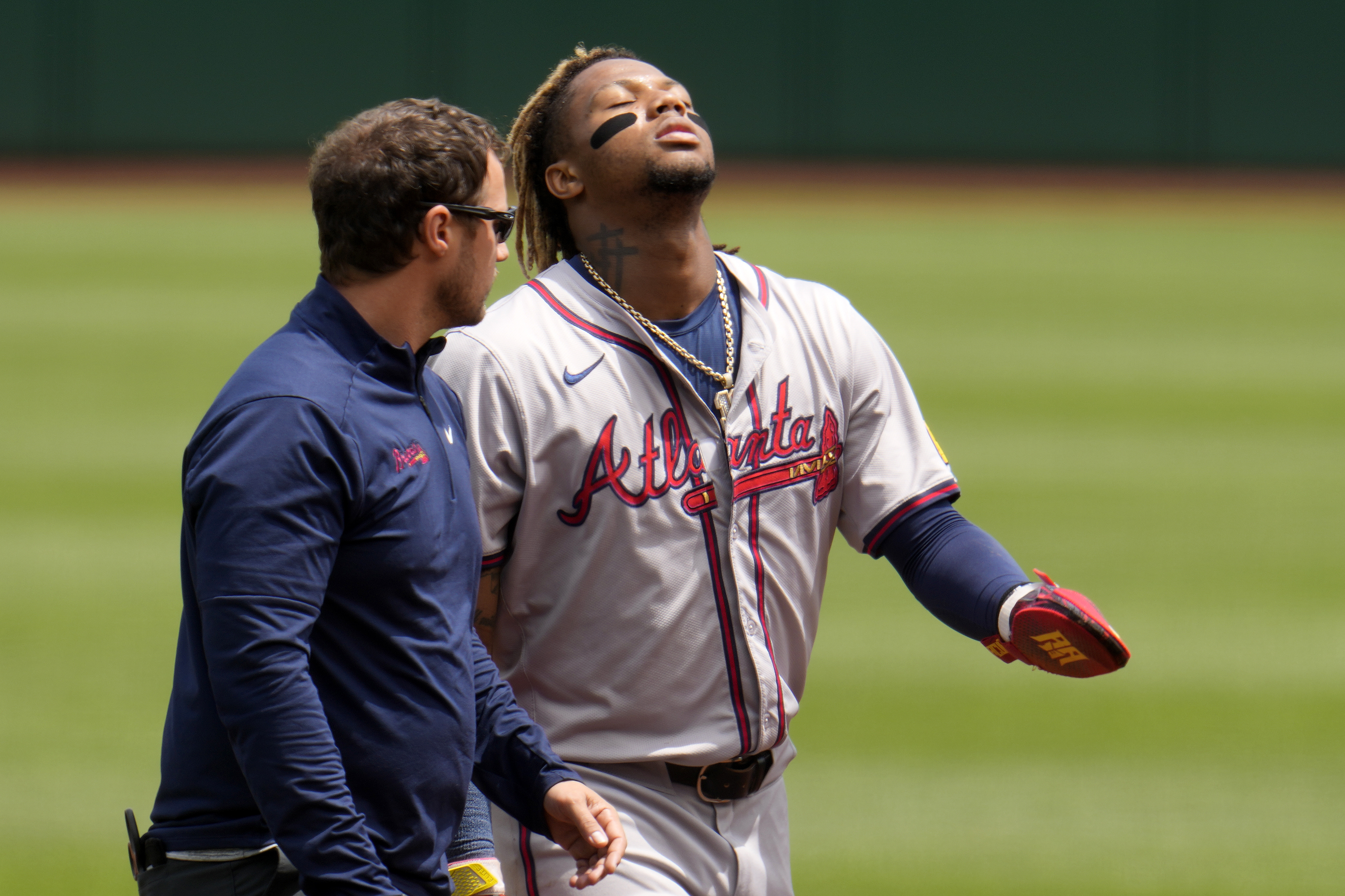 Atlanta Braves' Ronald Acuña Jr., right, walks off the field with a trainer after being injured while running the bases during the first inning of a baseball game against the Pittsburgh Pirates in Pittsburgh, Sunday, May 26, 2024.