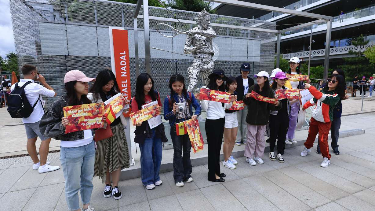 Fans of Spain's Rafael Nadal pose for pictures with his statue ahead of his first round match of the French Open tennis tournament against Germany's Alexander Zverev at the Roland Garros stadium in Paris, Monday, May 27, 2024.