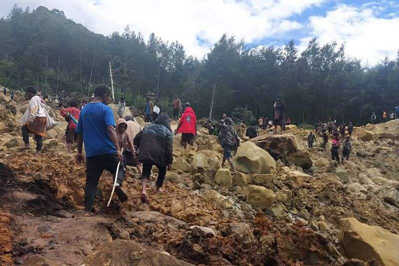 People cross over the landslide area to get to the other side in Yambali village, Papua New Guinea, Friday.