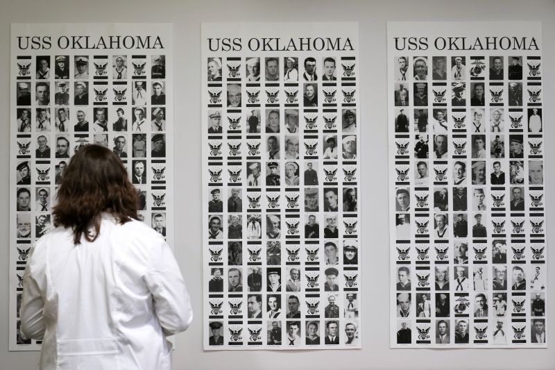 Defense POW/MIA Accounting Agency forensic anthropologist Carrie Brown looks at photos of service members from the USS Oklahoma on a wall at Offutt Air Force Base, May 20 in Bellevue, Neb.