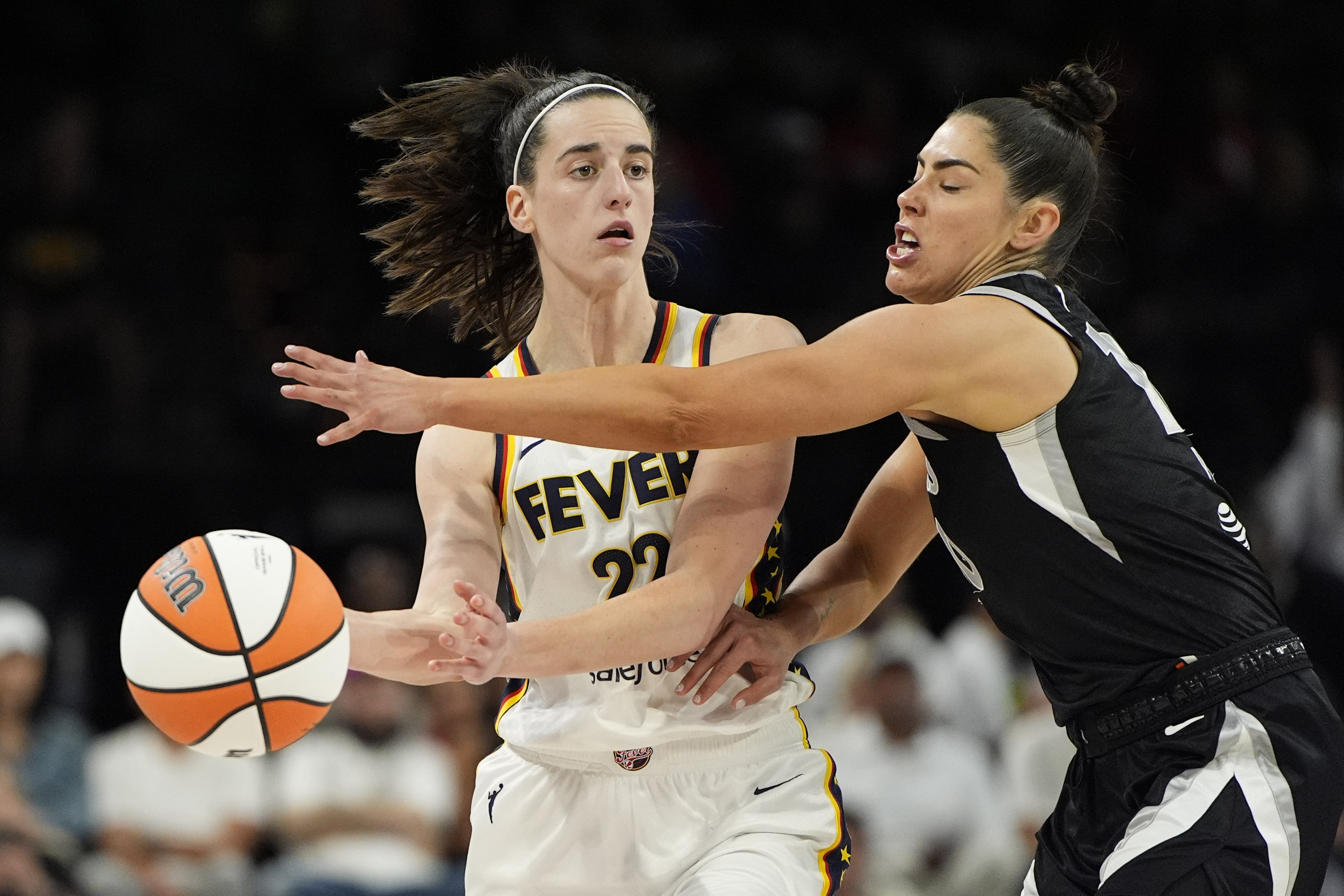 Indiana Fever guard Caitlin Clark (22) passes around Las Vegas Aces guard Kelsey Plum during the second half of a WNBA basketball game Saturday, May 25, 2024, in Las Vegas. 