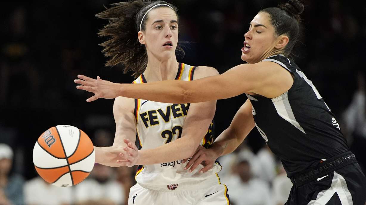 Indiana Fever guard Caitlin Clark (22) passes around Las Vegas Aces guard Kelsey Plum during the second half of a WNBA basketball game Saturday, May 25, 2024, in Las Vegas.