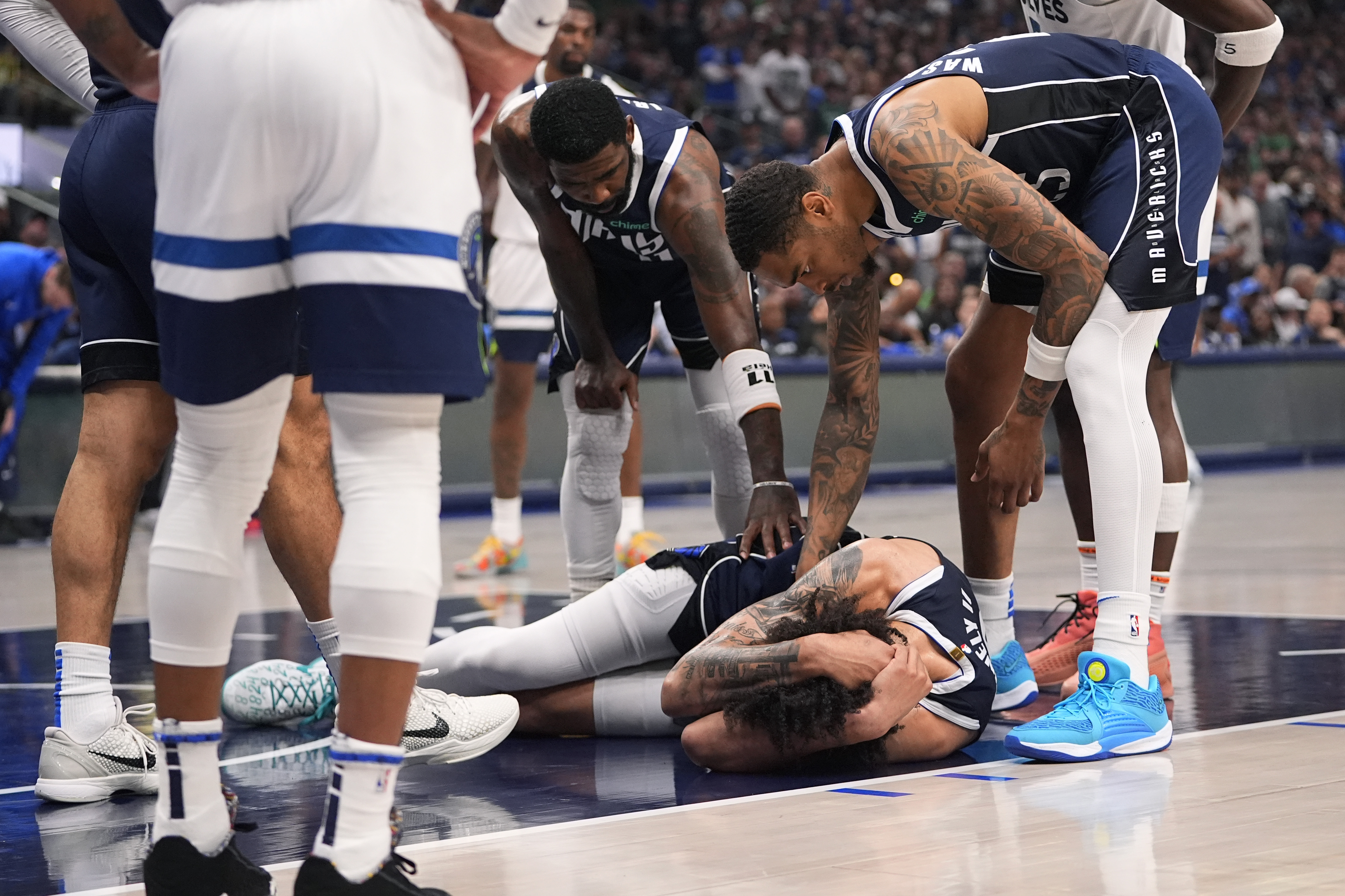 Dallas Mavericks center Dereck Lively II (2) is checked on by teammates after a head injury during the first half in Game 3 of the NBA basketball Western Conference finals against the Minnesota Timberwolves, Sunday, May 26, 2024, in Dallas. 