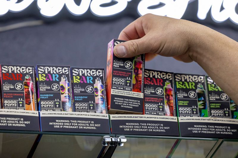 Anes Saleh, owner of Sultans' Smoke, takes a package of the Spree Bar, which contains a new chemical that mimics nicotine, from the shelf of his store in Arvada, Colo., May 21.