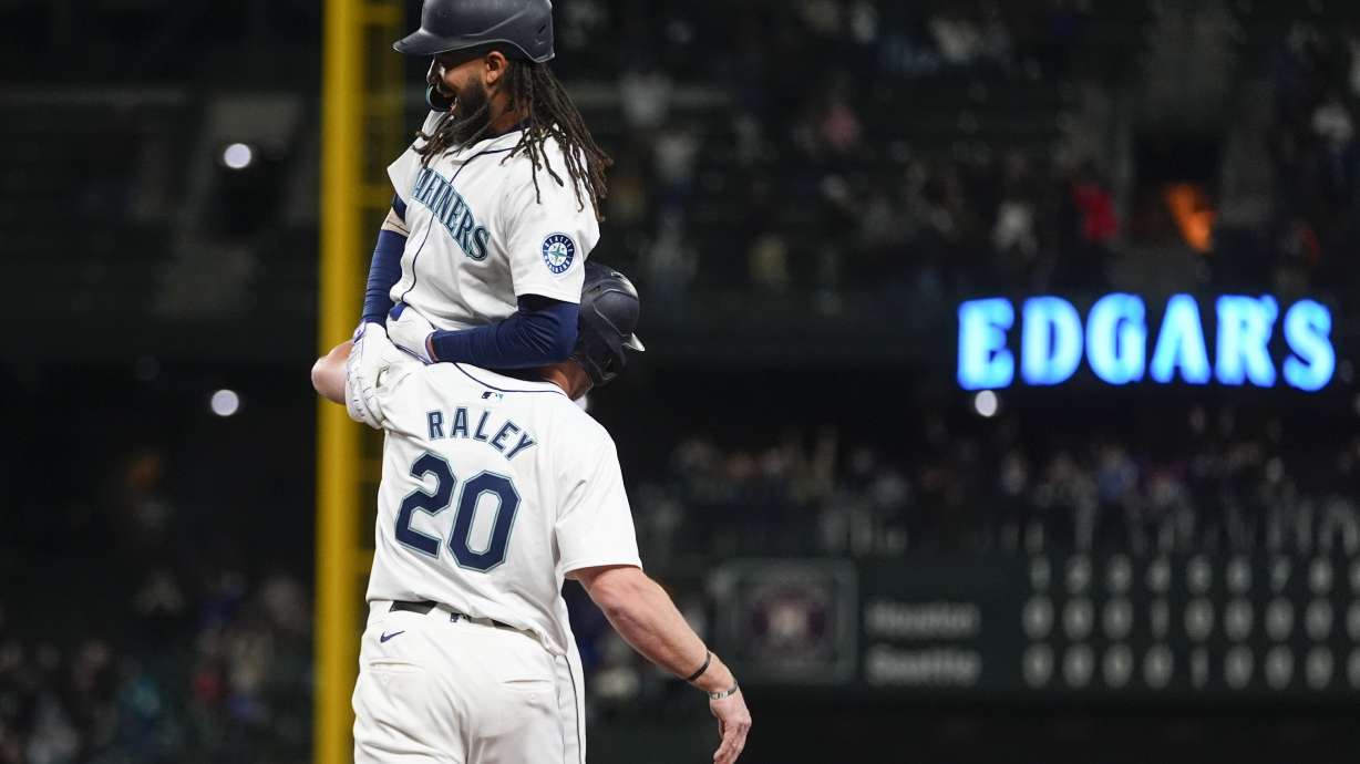 Seattle Mariners' J.P. Crawford is lifted by Luke Raley (20) after driving in the winning run against the Houston Astros with a sacrifice fly during the 10th inning of a baseball game, Wednesday, May 29, 2024, in Seattle. The Mariners won 2-1.