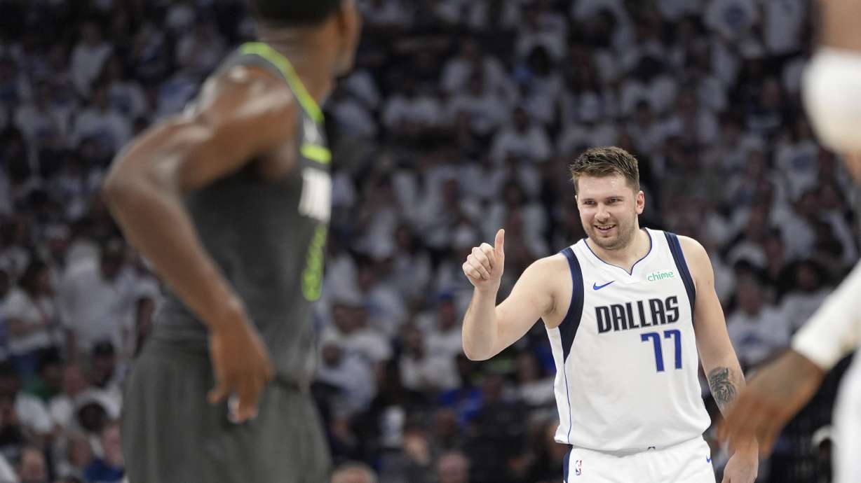 Dallas Mavericks guard Luka Doncic (77) celebrates his score as Minnesota Timberwolves guard Anthony Edwards, left, looks on during the first half of Game 5 of the Western Conference finals in the NBA basketball playoffs, Thursday, May 30, 2024, in Minneapolis.
