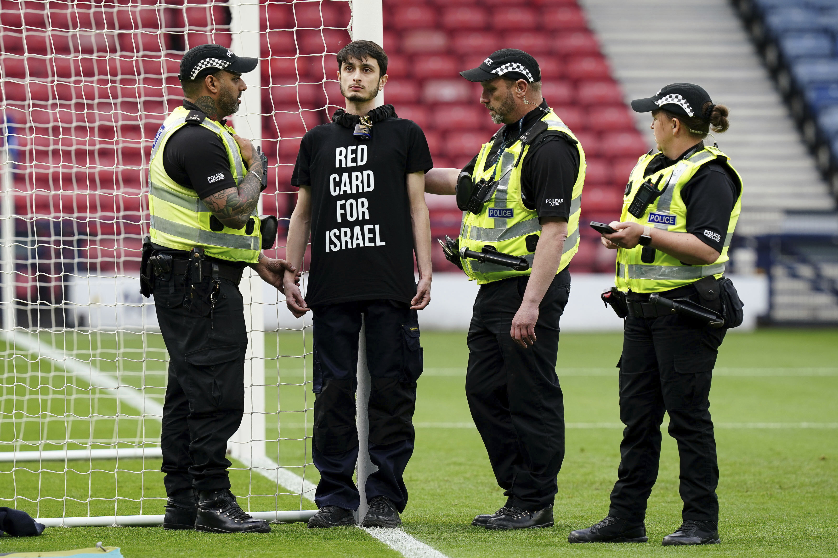 Police speak to a protestor wearing a "Red Card For Israel" T-Shirt after he chained himself to a goalpost ahead of the UEFA Women's Euro 2025 qualifying match between Scotland and Israel, at Hampden Park in Glasgow, Scotland, Friday May 31, 2024. 