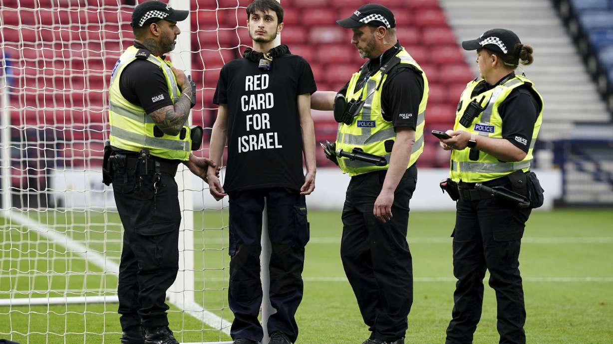 Police speak to a protestor wearing a "Red Card For Israel" T-Shirt after he chained himself to a goalpost ahead of the UEFA Women's Euro 2025 qualifying match between Scotland and Israel, at Hampden Park in Glasgow, Scotland, Friday May 31, 2024.