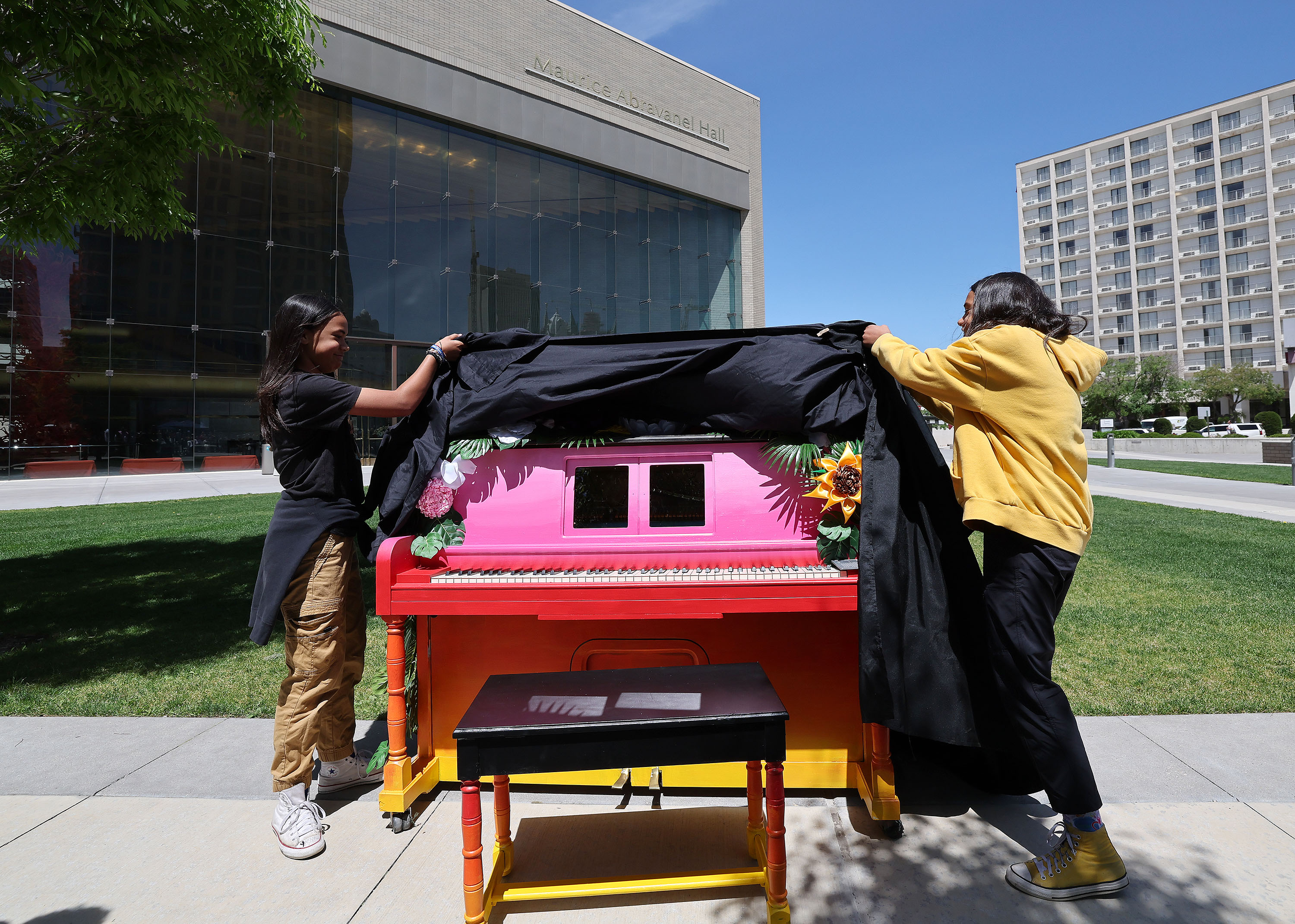 Kalea and Kamila Tukuafu uncover their mother's decorated piano during a public art installation of upcycled pianos at Abravanel Hall Plaza in Salt Lake City on Friday.