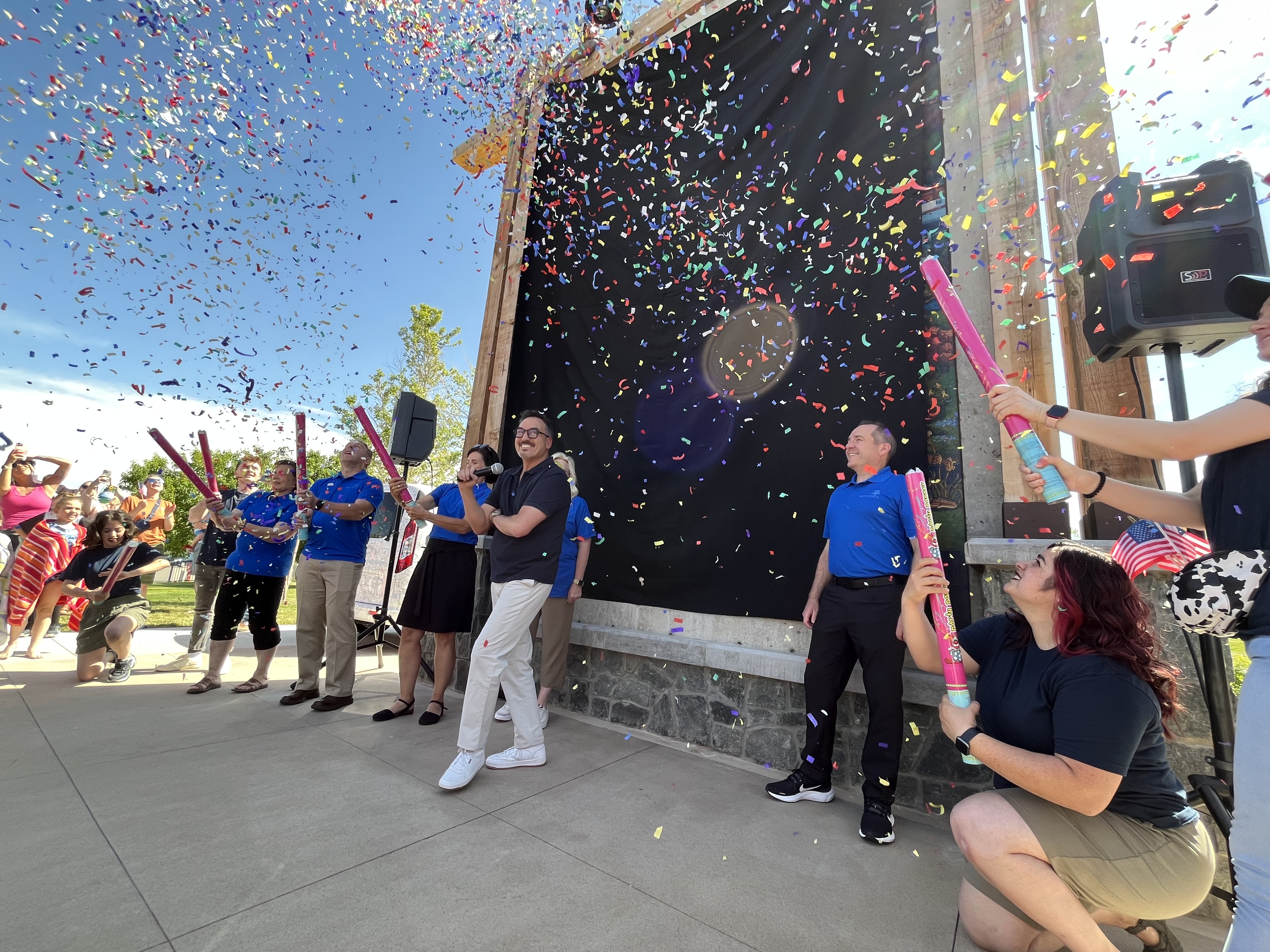 American Folk Ensemble dancers pop confetti as Eric Dowdle drops the curtain on his latest mural in South Jordan's Heritage Park.